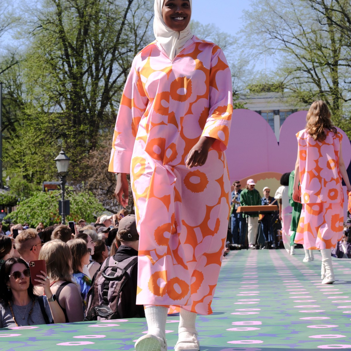 Model wearing orange and pink dress with Unikko pattern.