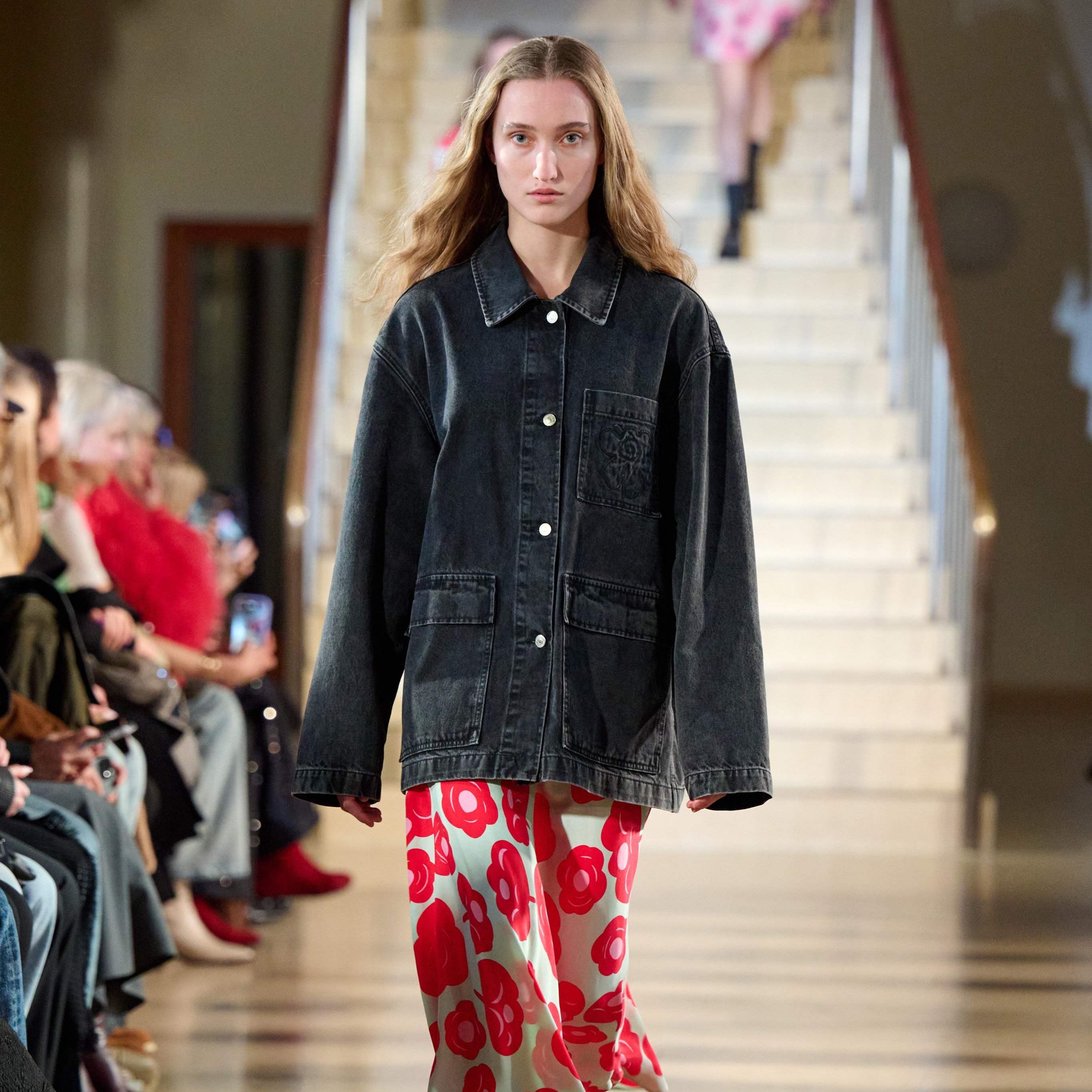 A model walks in the Marimekko fashion show wearing an oversized Maridenim jacket and a red dress
