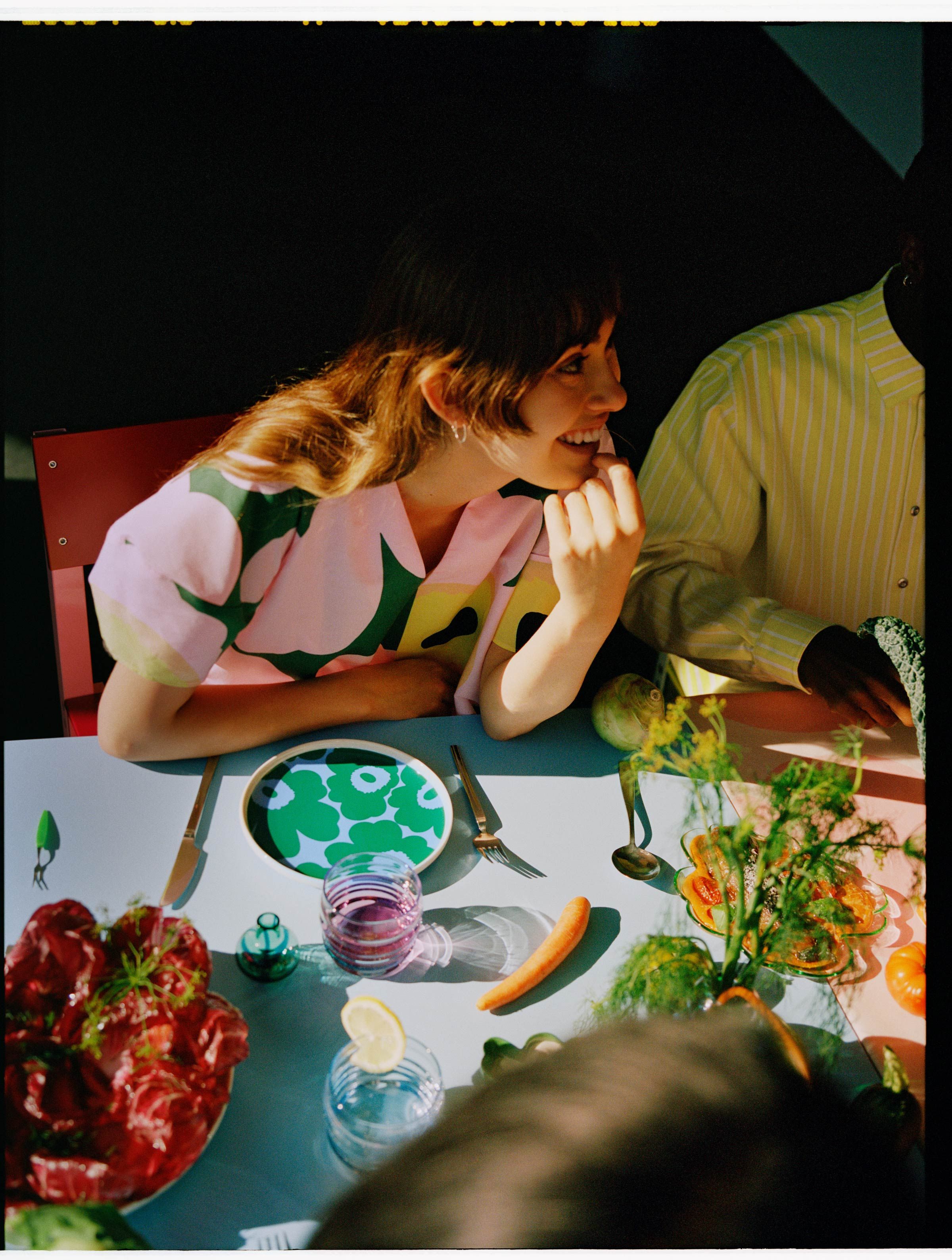 Model wearing a Unikko dress at the dinner table with colorful Unikko tableware.