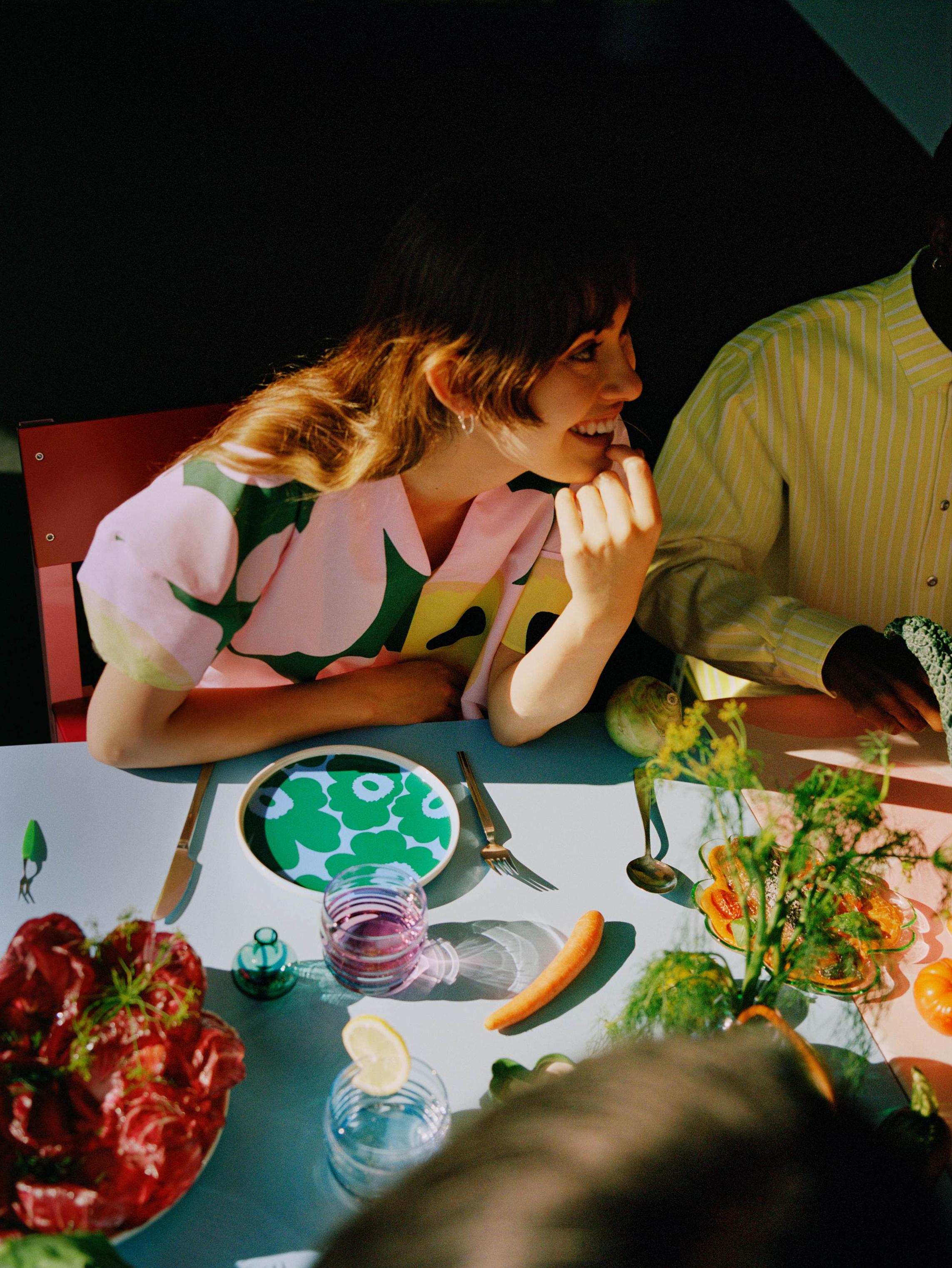 Model wearing a Unikko dress at the dinner table with colorful Unikko tableware.
