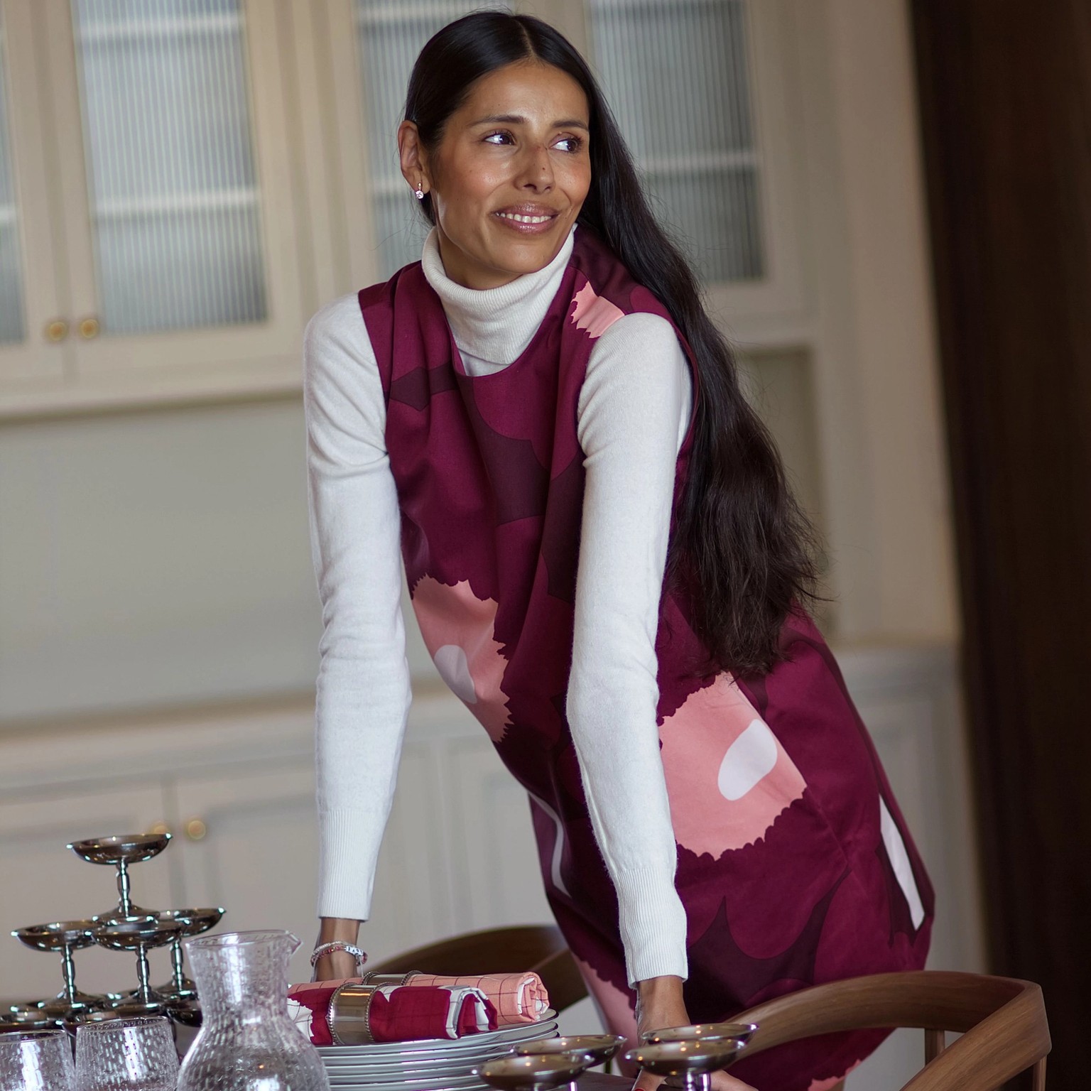 Babba C. Rivera is leaning on table and wearing red Unikko-dress