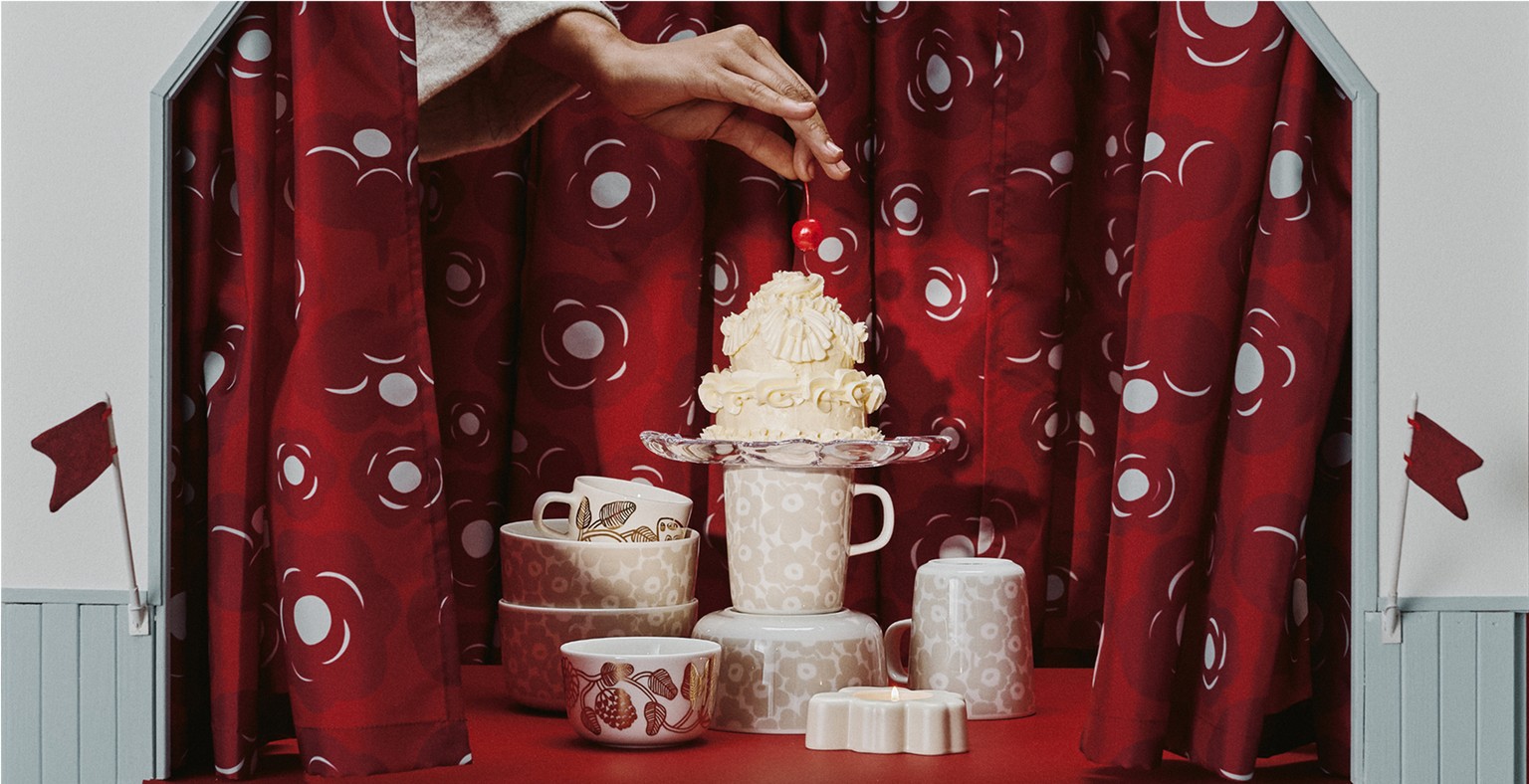 Stacked White Unikko and Tiara tableware displayed on a stage with a cake placed on top.