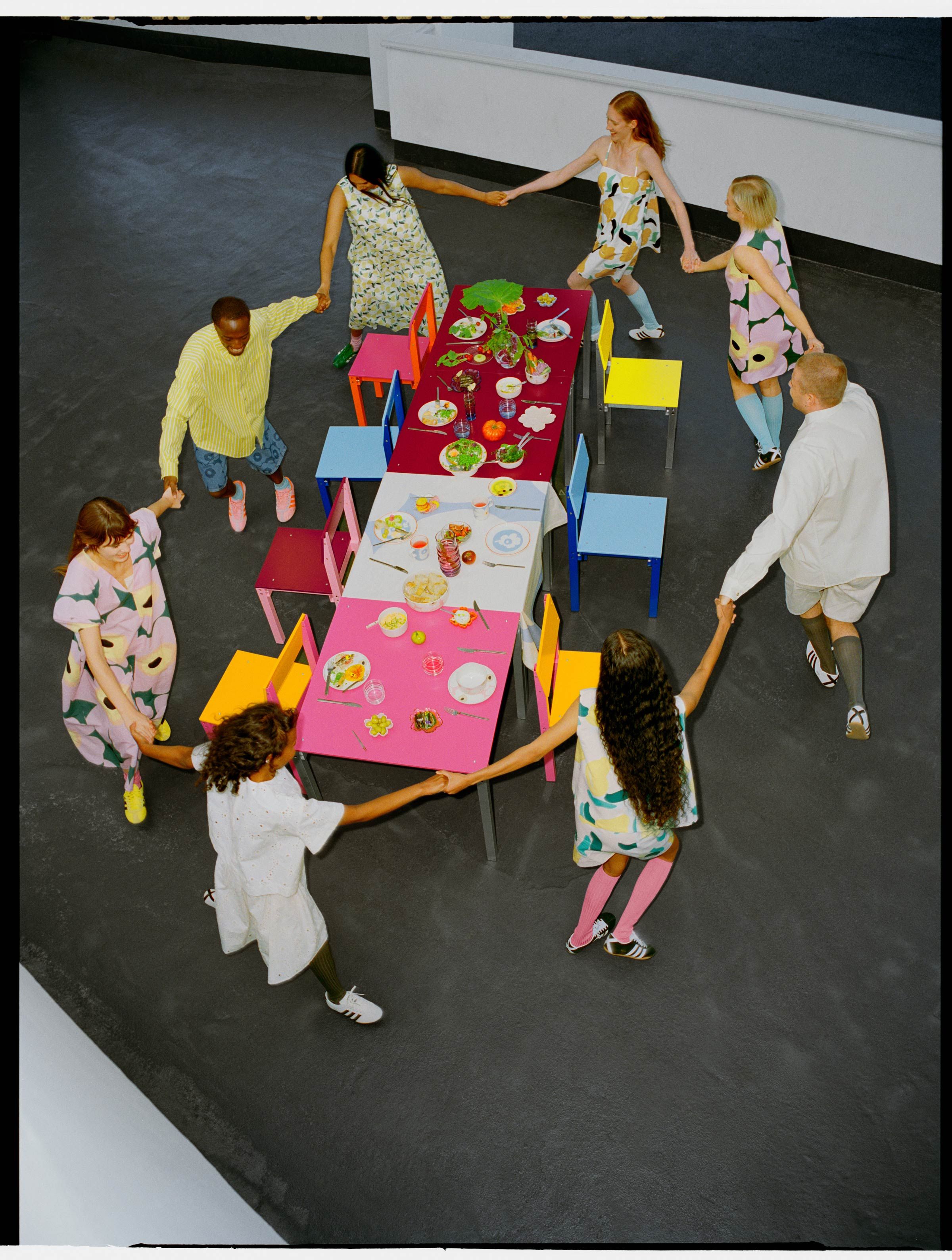 Models wearing various Marimekko pieces dancing around a colorful table.