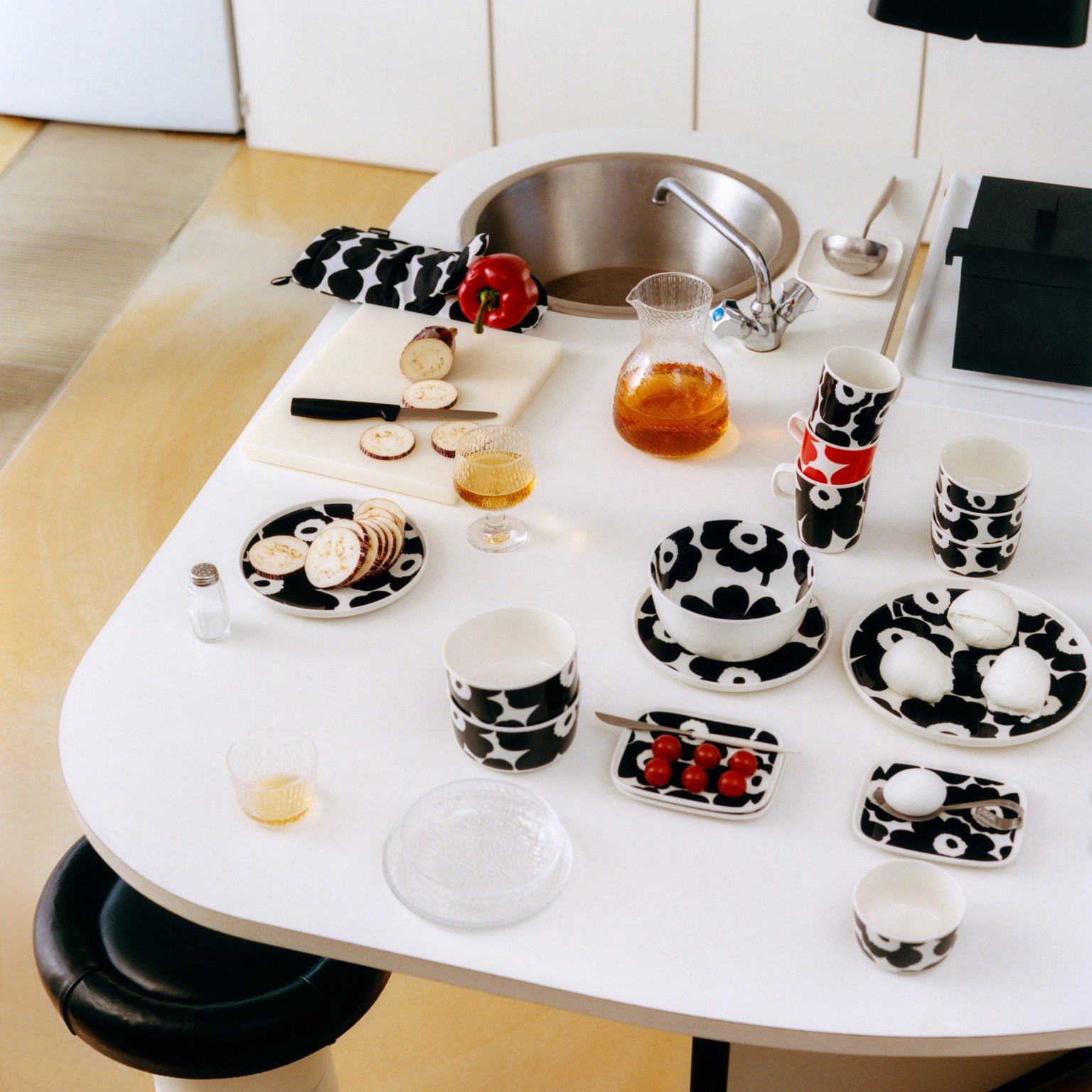 Unikko-astioita ja lasiastioita valkoisella pöydällä.