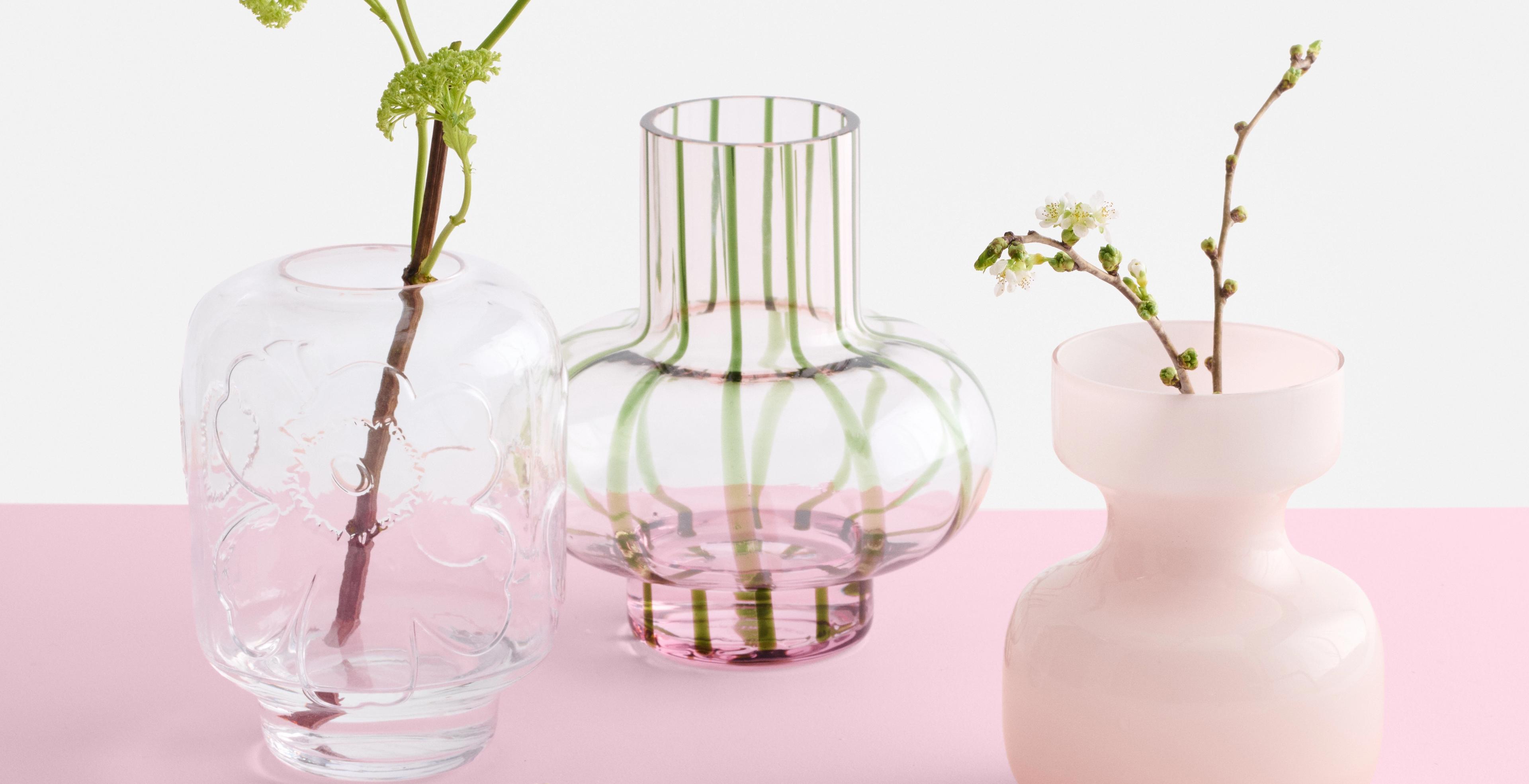 Three vases in shades of pink and clear glass displayed on a pink tabletop