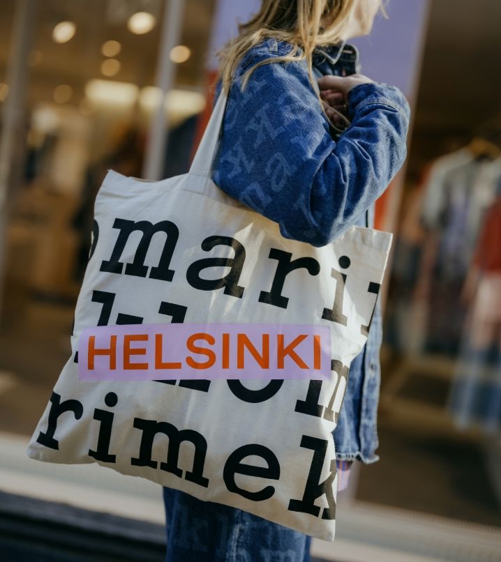 Nainen Maridenim-paita päällään kantamassa Helsinki-logokassia.