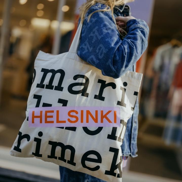 Nainen Maridenim-paita päällään kantamassa Helsinki-logokassia.