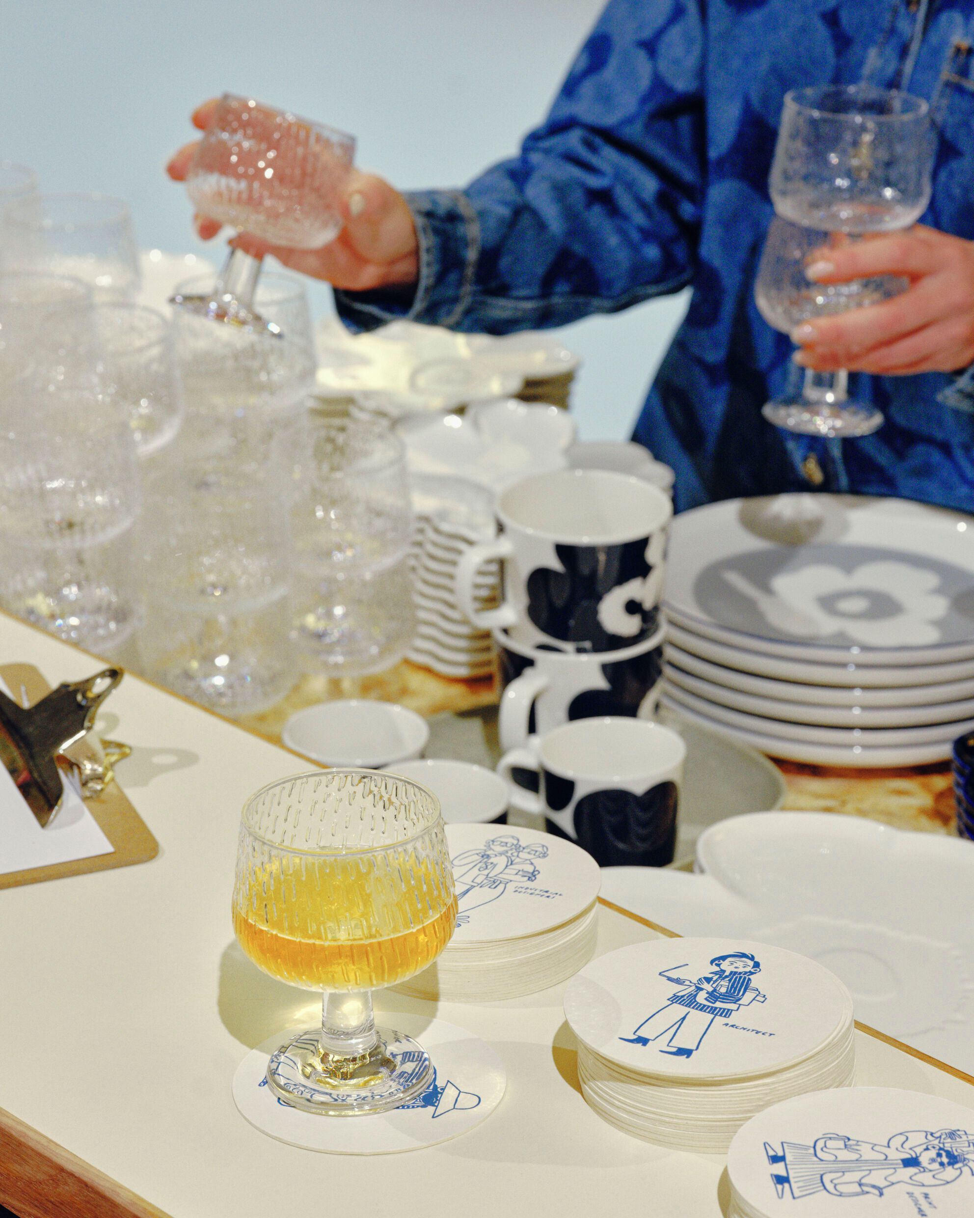 A waiter arranging the Syksy glass series wine glasses in a Maridenim outfit