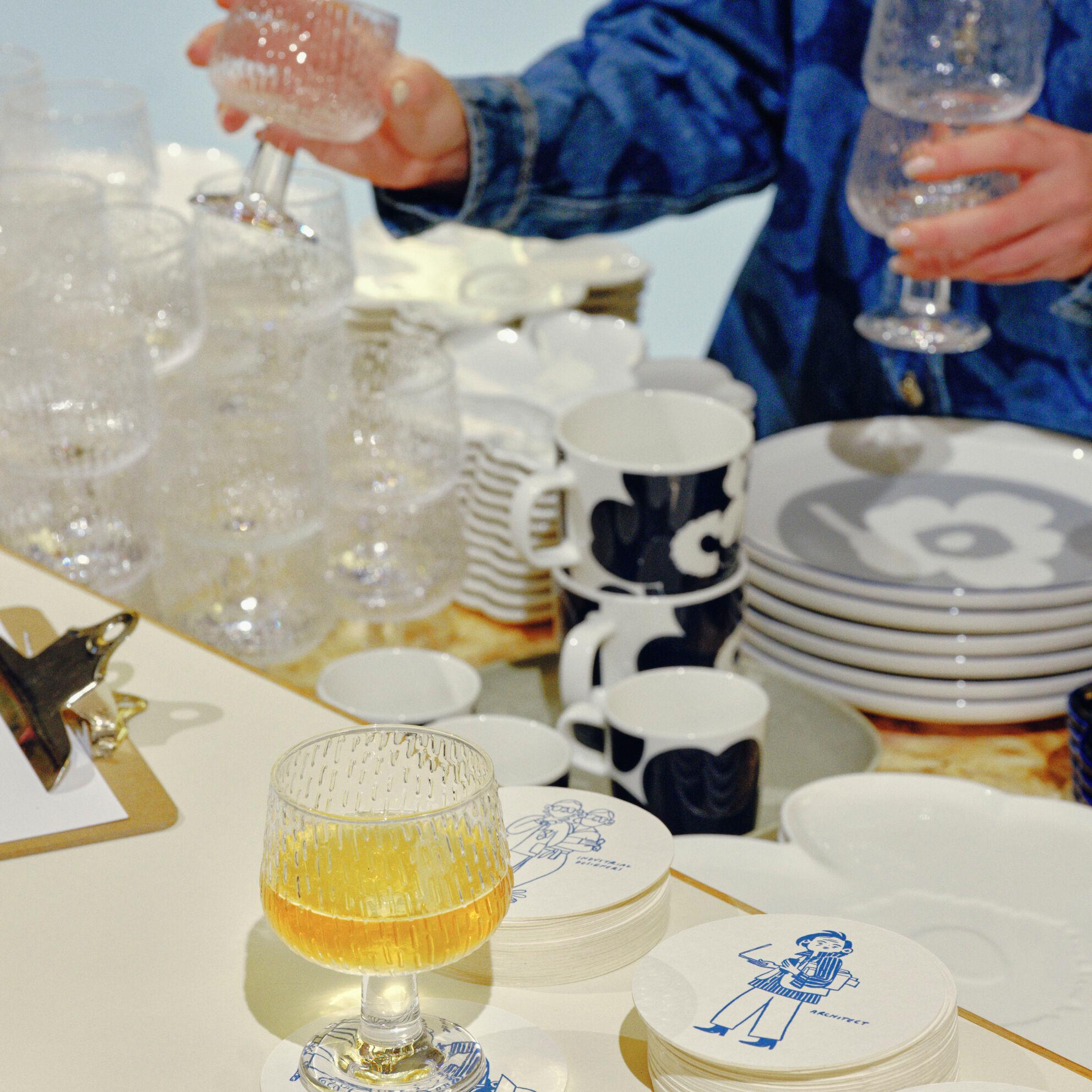 A waiter arranging the Syksy glass series wine glasses in a Maridenim outfit