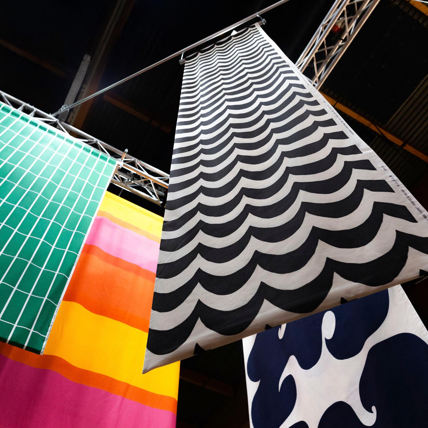 Fabrics hanging from the ceiling, with patterns: Annika Rimala's Laine and Jokeri patterns, Armi Ratia's Tiiliskivi pattern and Vuokko Eskolin-Nurmesniemi's Hennika pattern.