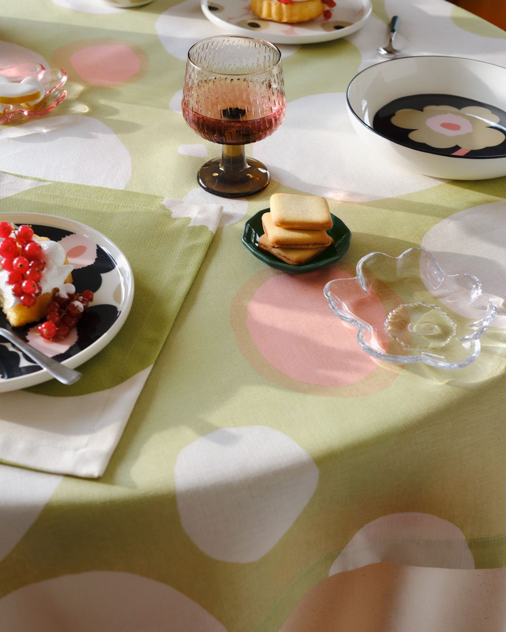 Tablesetting with Unikko-printed tableware, Unikko-shaped glass plate and a tablecloth in Keidas print.
