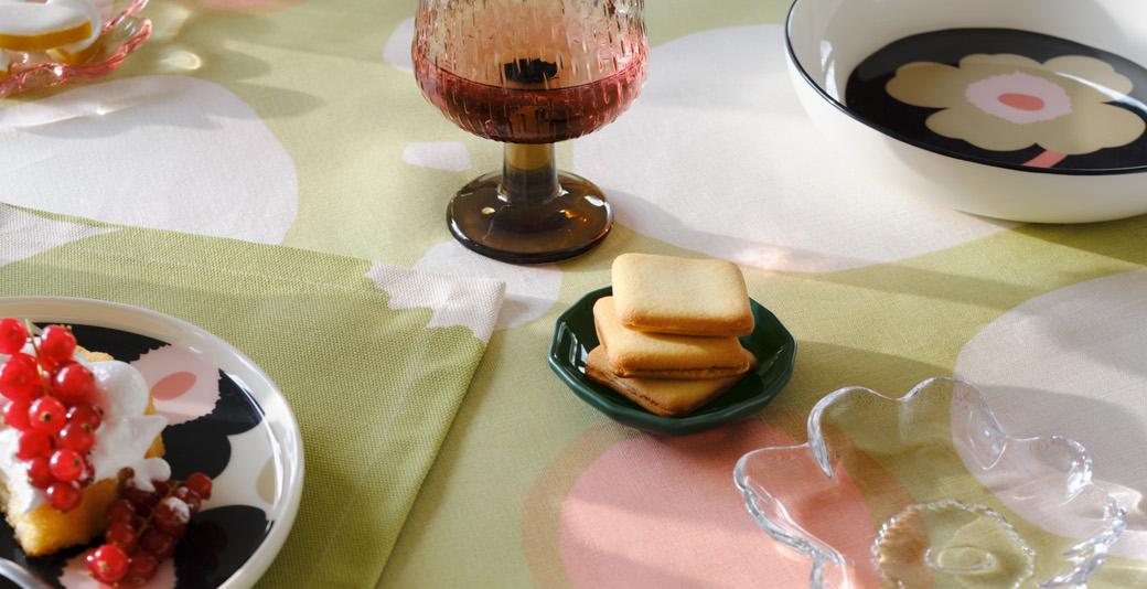 Tablesetting with Unikko-printed tableware, Unikko-shaped glass plate and a tablecloth in Keidas print.
