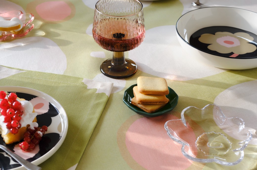 Tablesetting with Unikko-printed tableware, Unikko-shaped glass plate and a tablecloth in Keidas print.