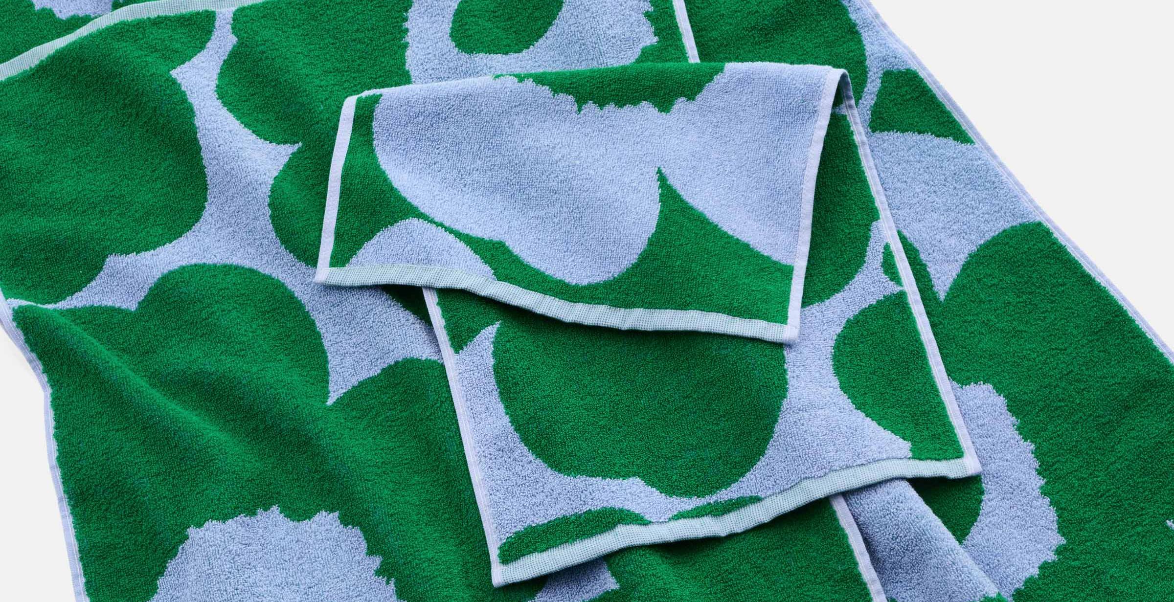 Different sized green and blue Unikko towels spread on a flat surface.