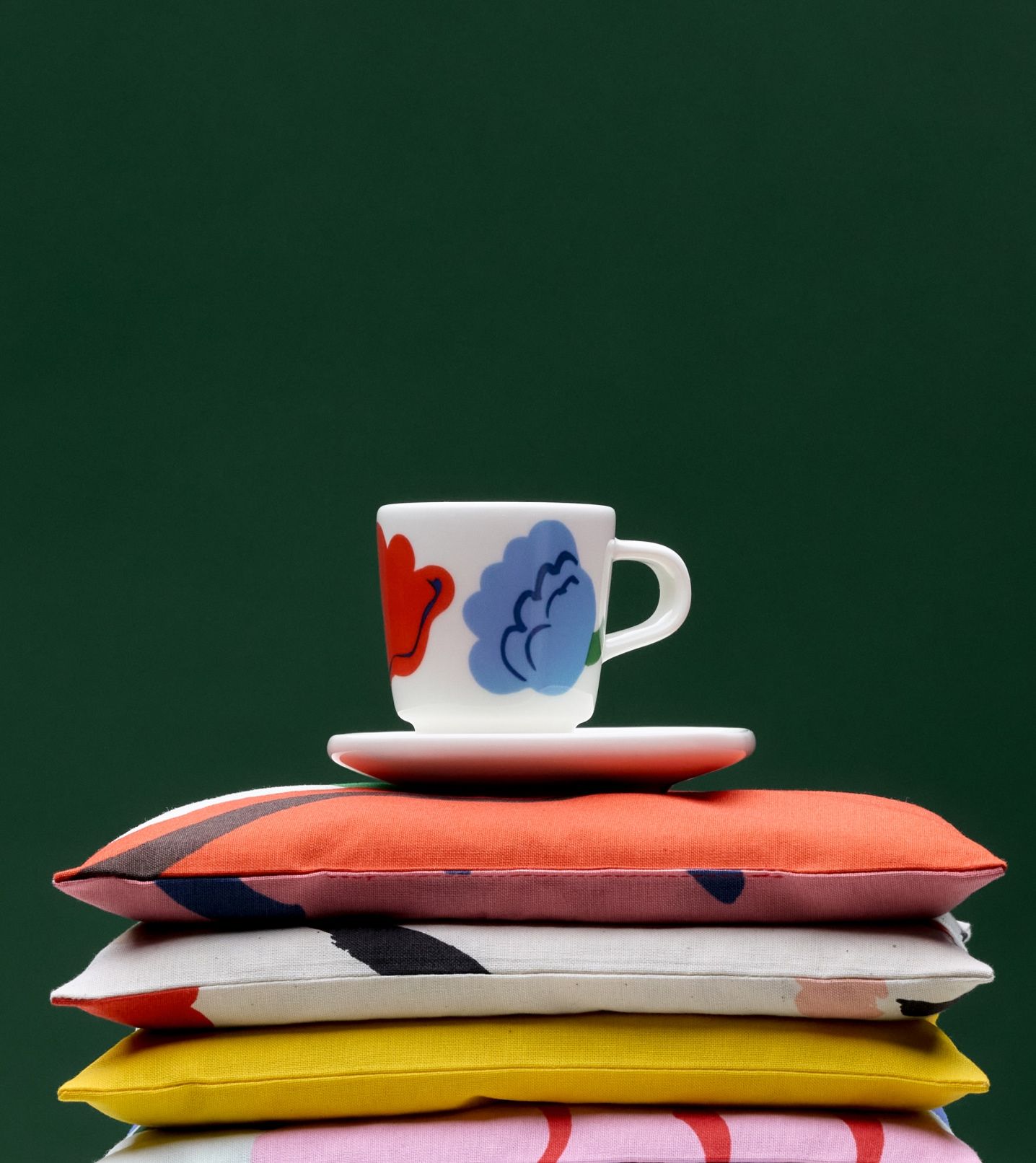 An espresso cup and saucer with Kukasta kukkaan print placed on pillows.