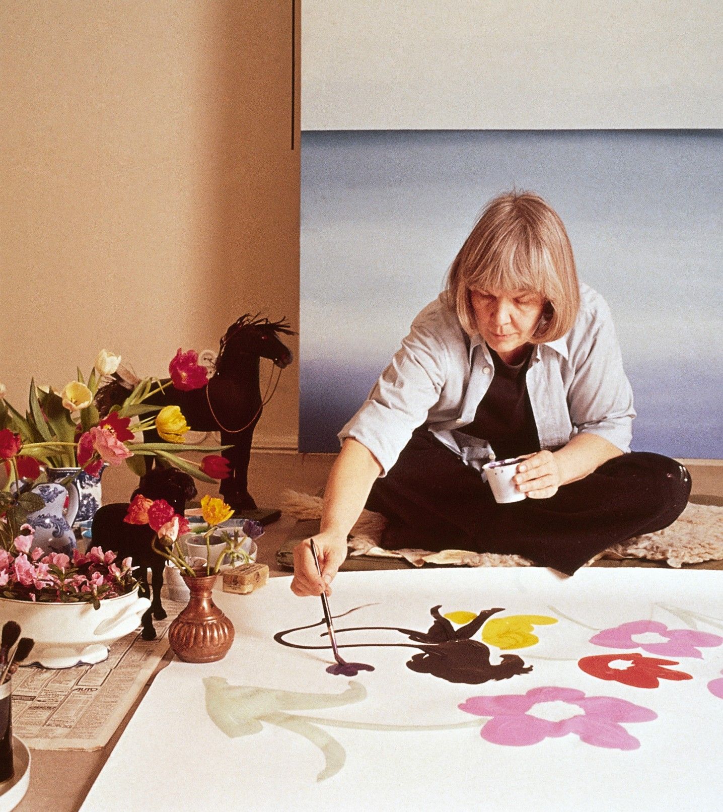 Maija Isola sitting and painting.