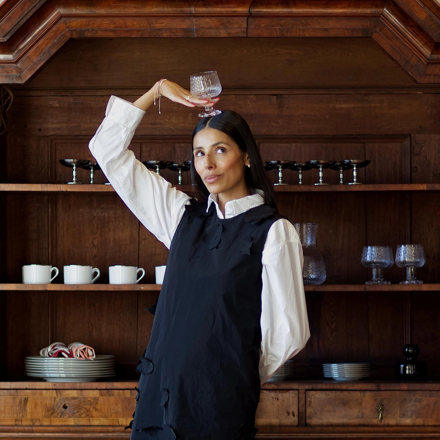 Babba C. Riviera dressed in a black Marimekko dress and holding a Syksy glassware wine glass