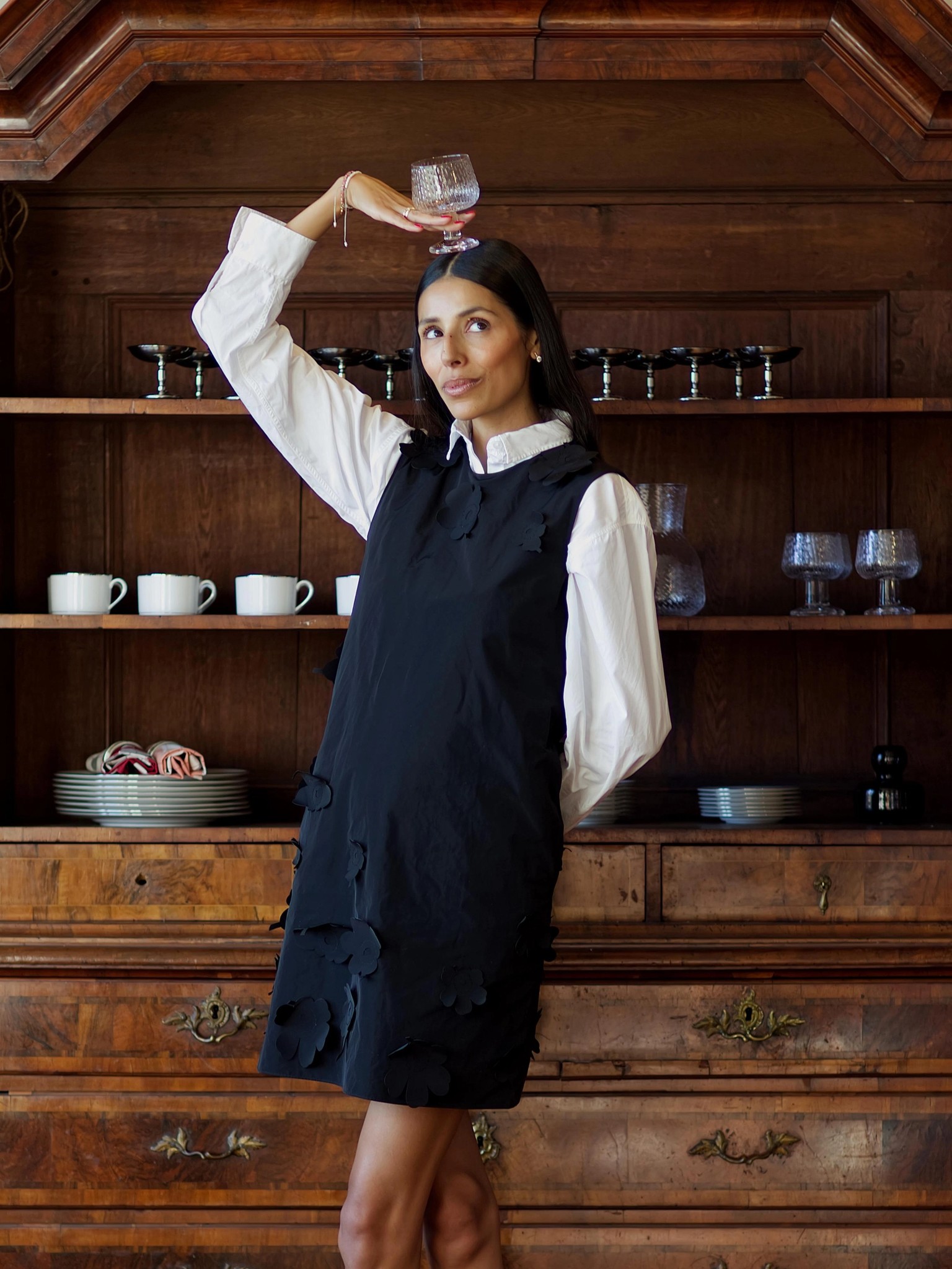 Babba C. Riviera dressed in a black Marimekko dress and holding a Syksy glassware wine glass