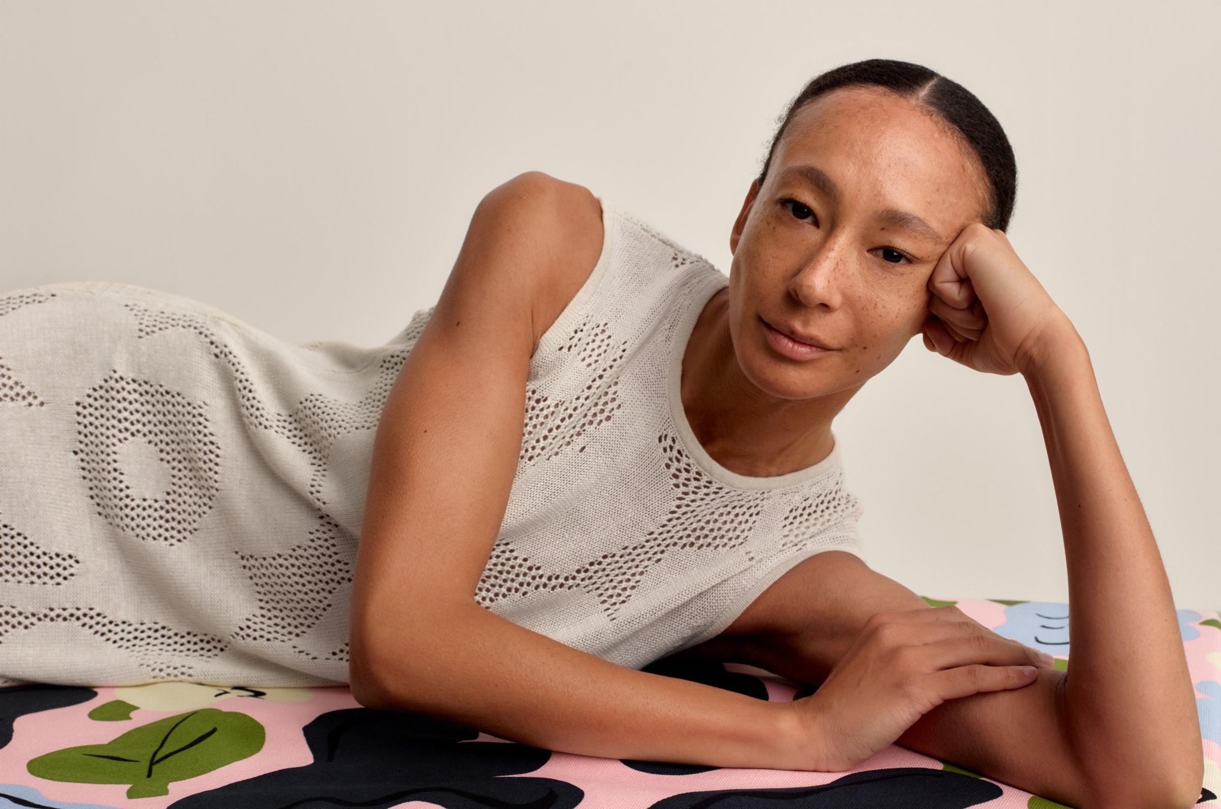 Model wearing a long and sleeveless white pointelle dress in Unikko print.