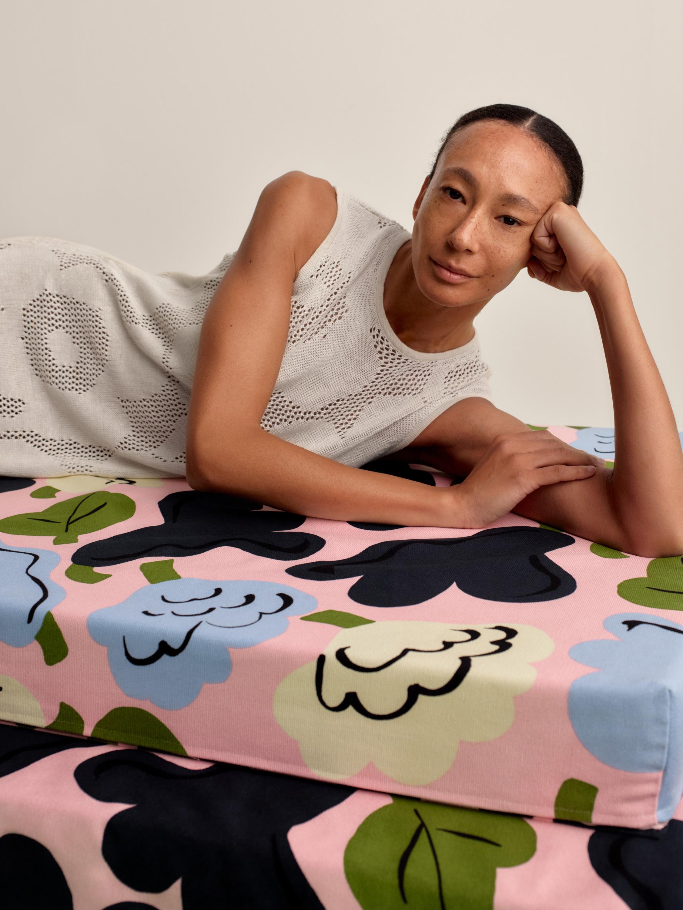Model wearing a long and sleeveless white pointelle dress in Unikko print.