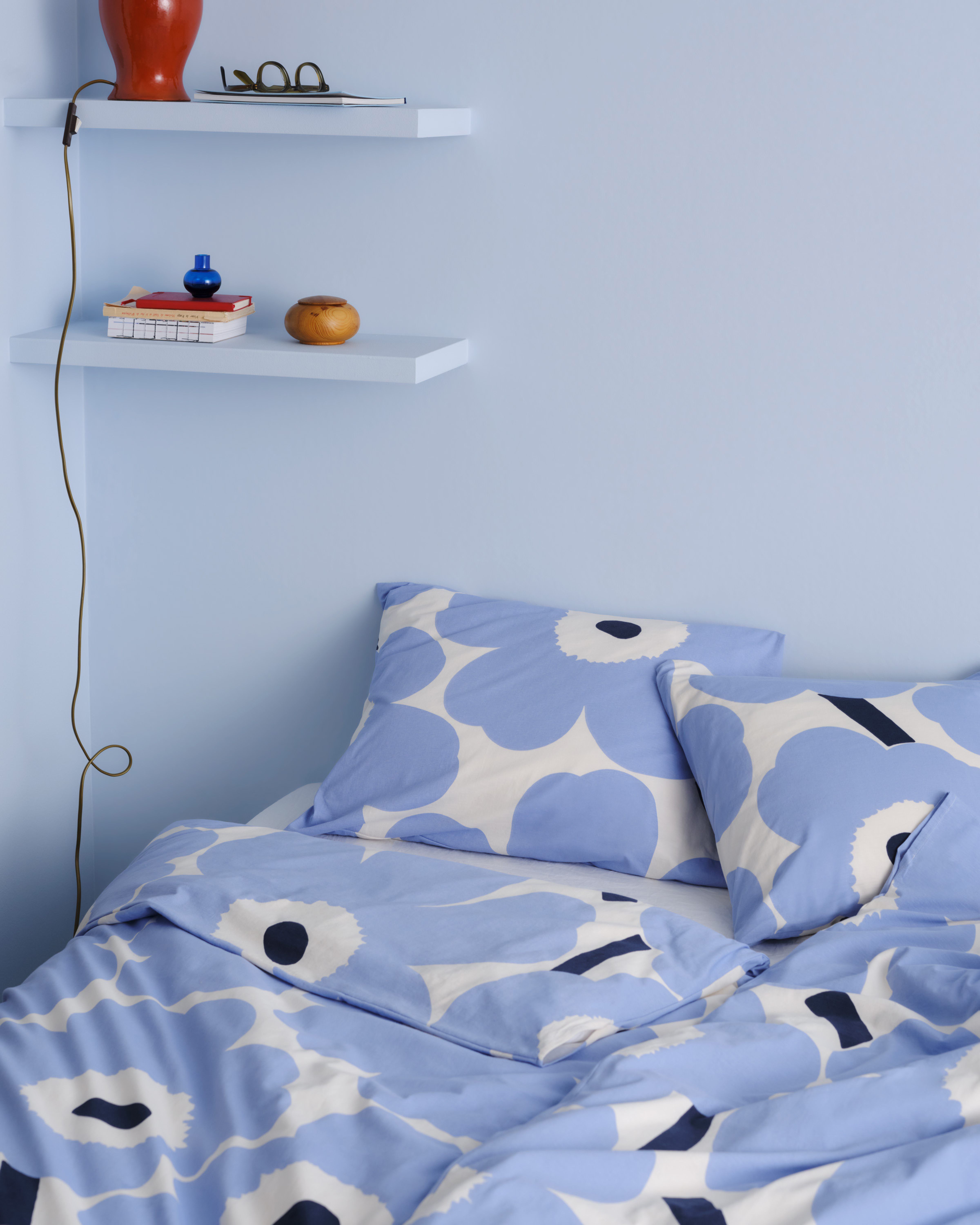 Blue and white Unikko-printed duvet covers and pillow cases on a bed.