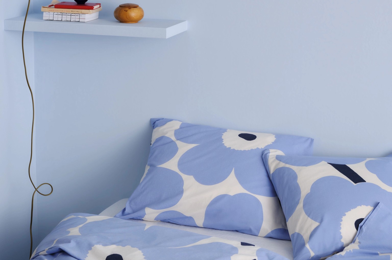 Blue and white Unikko-printed duvet covers and pillow cases on a bed.