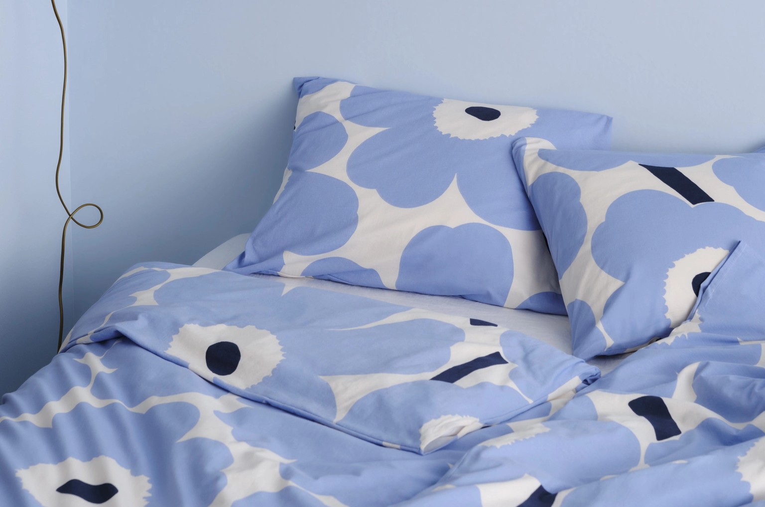 Blue and white Unikko-printed duvet covers and pillow cases on a bed.