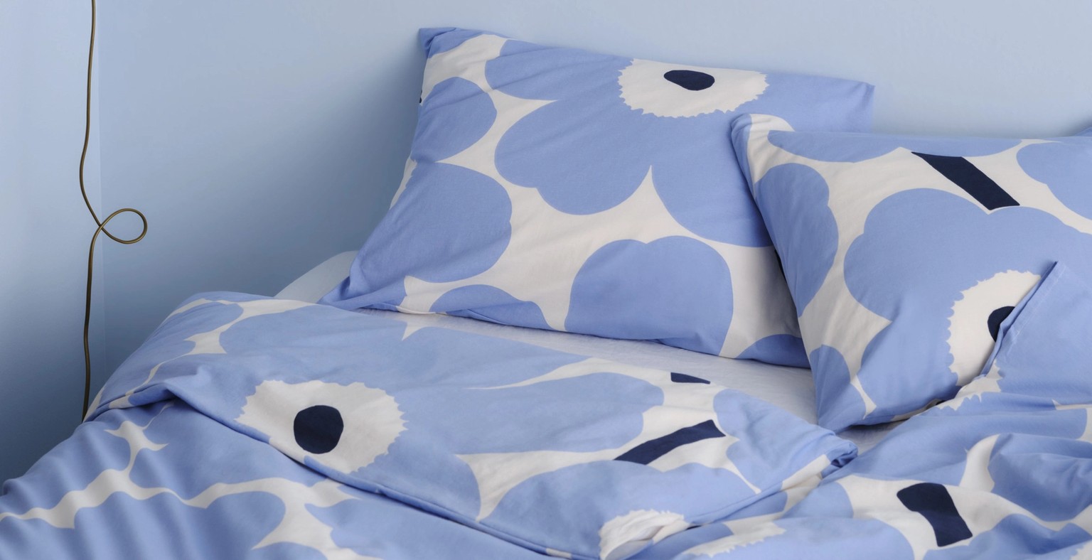 Blue and white Unikko-printed duvet covers and pillow cases on a bed.