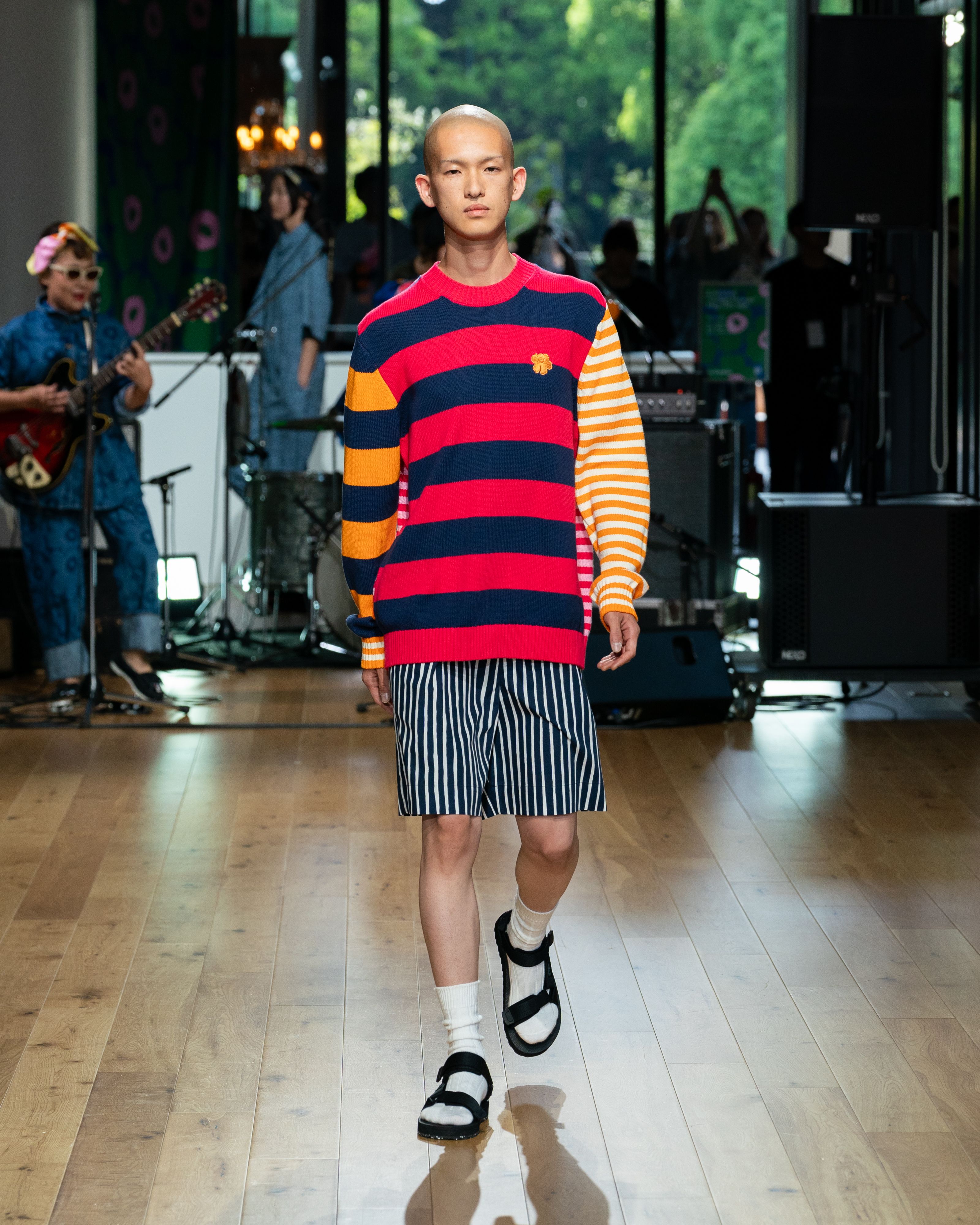 Model wearing striped colourful knit and blue Jokapoika shorts. 