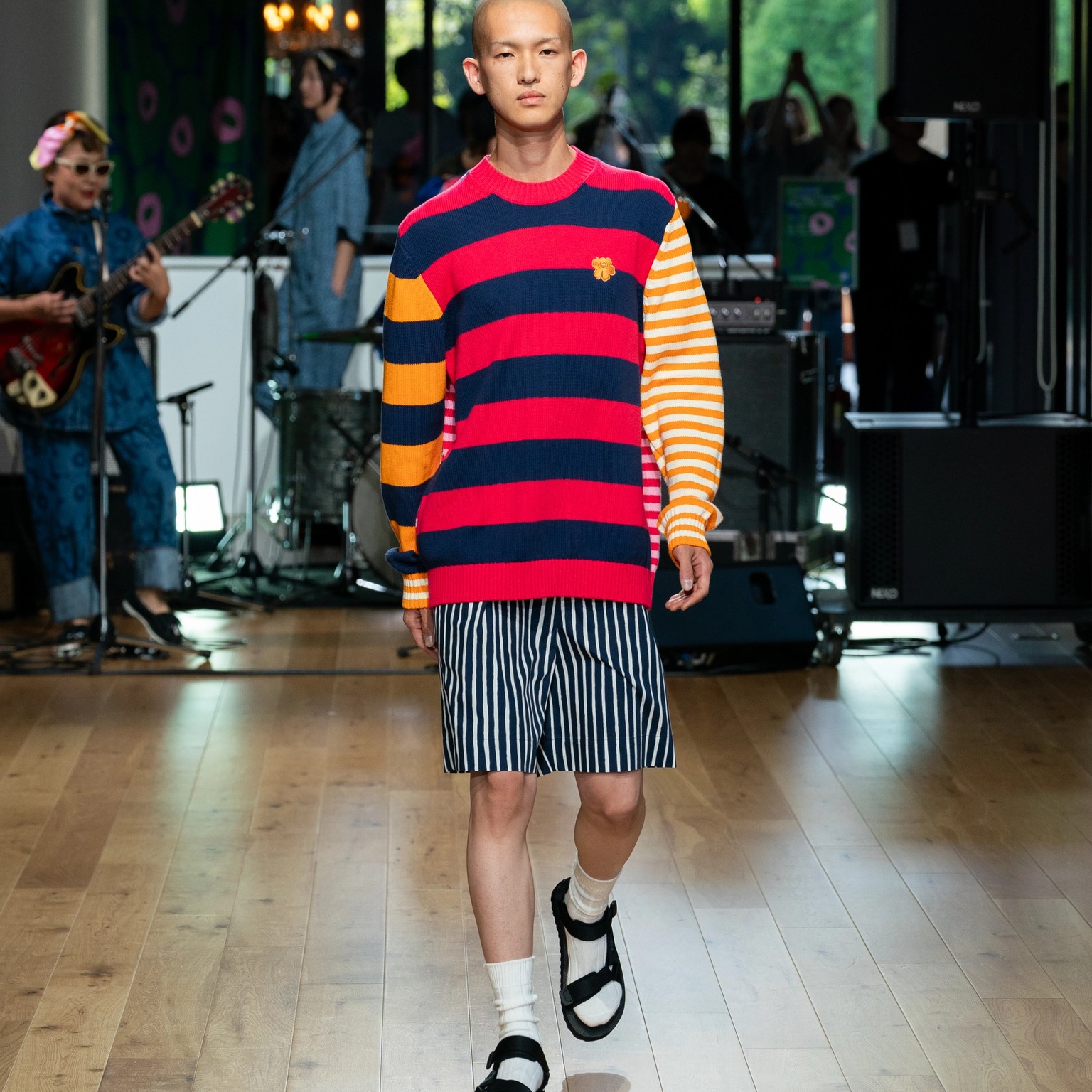 Model wearing striped colourful knit and blue Jokapoika shorts.