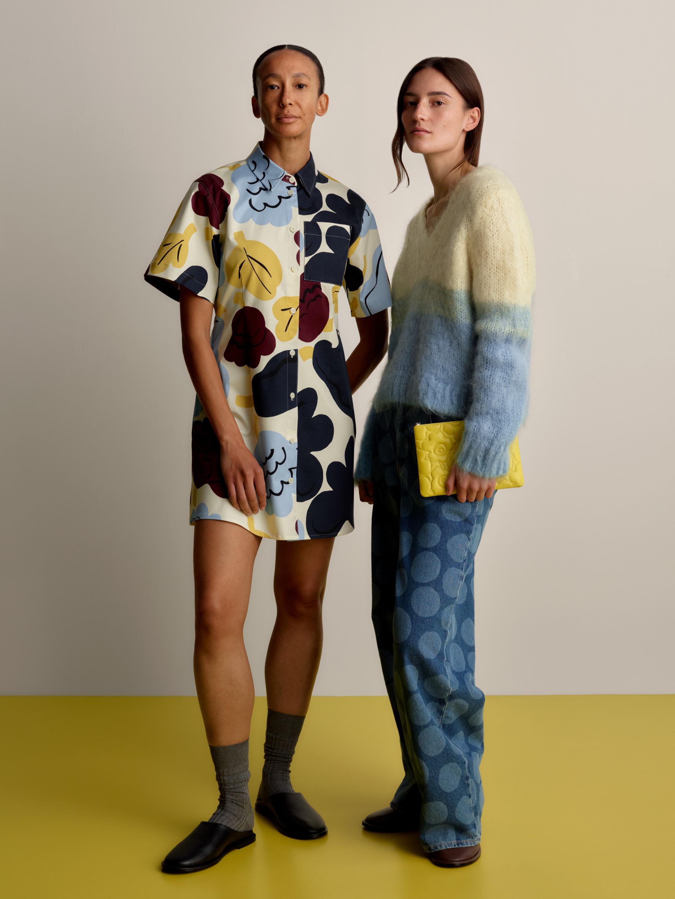 Two models, one wearing a Seikkailu dress in the Kukasta Kukkaan print and the other a Utuinen sweater and Maridenim Loose jeans in the Petrooli print.