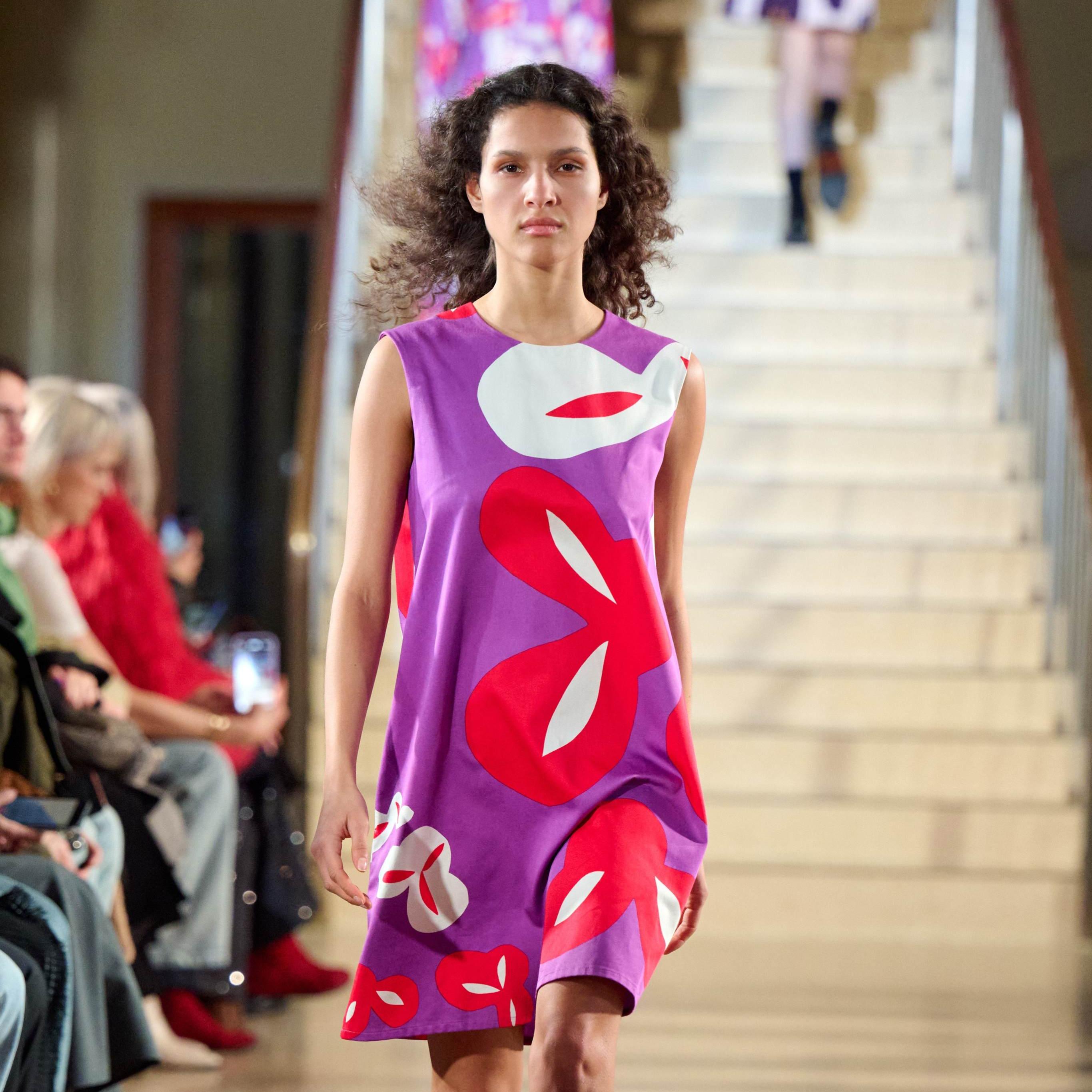 A model walks in the Marimekko fashion show wearing a light purple-pink Marimini dress
