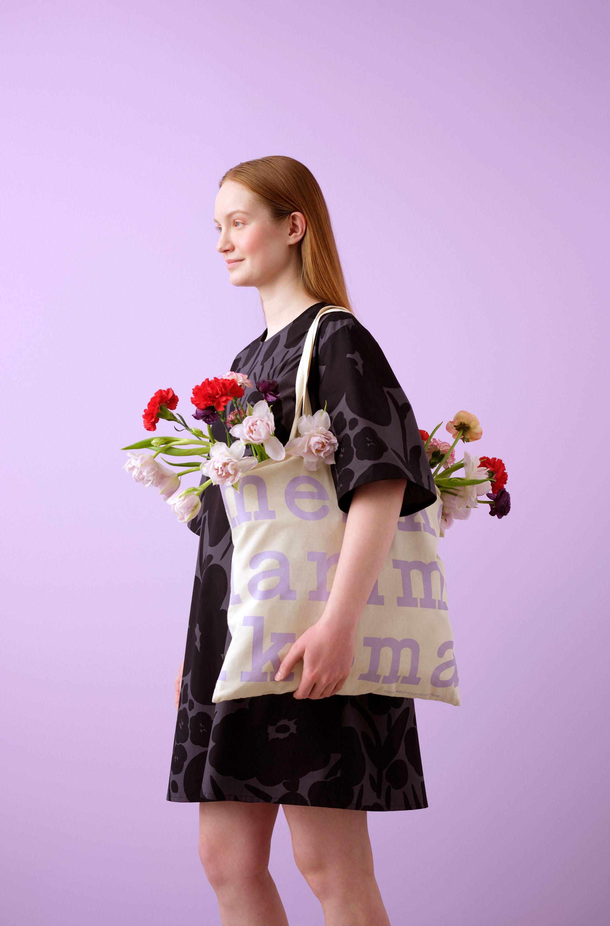 Mallilla musta Talkoot mekko ja logokassi, jossa kukkia.