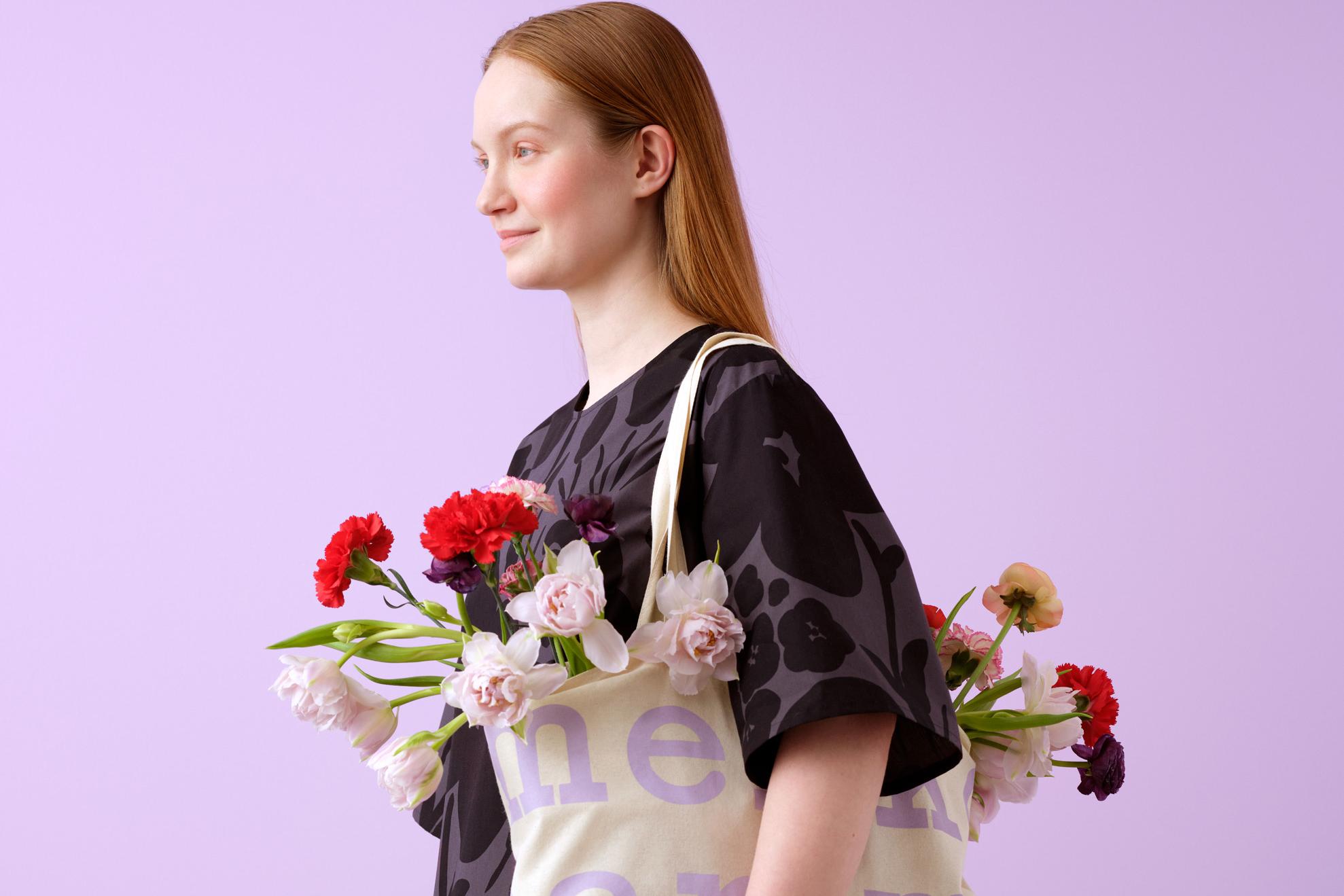 Mallilla musta Talkoot mekko ja logokassi, jossa kukkia.