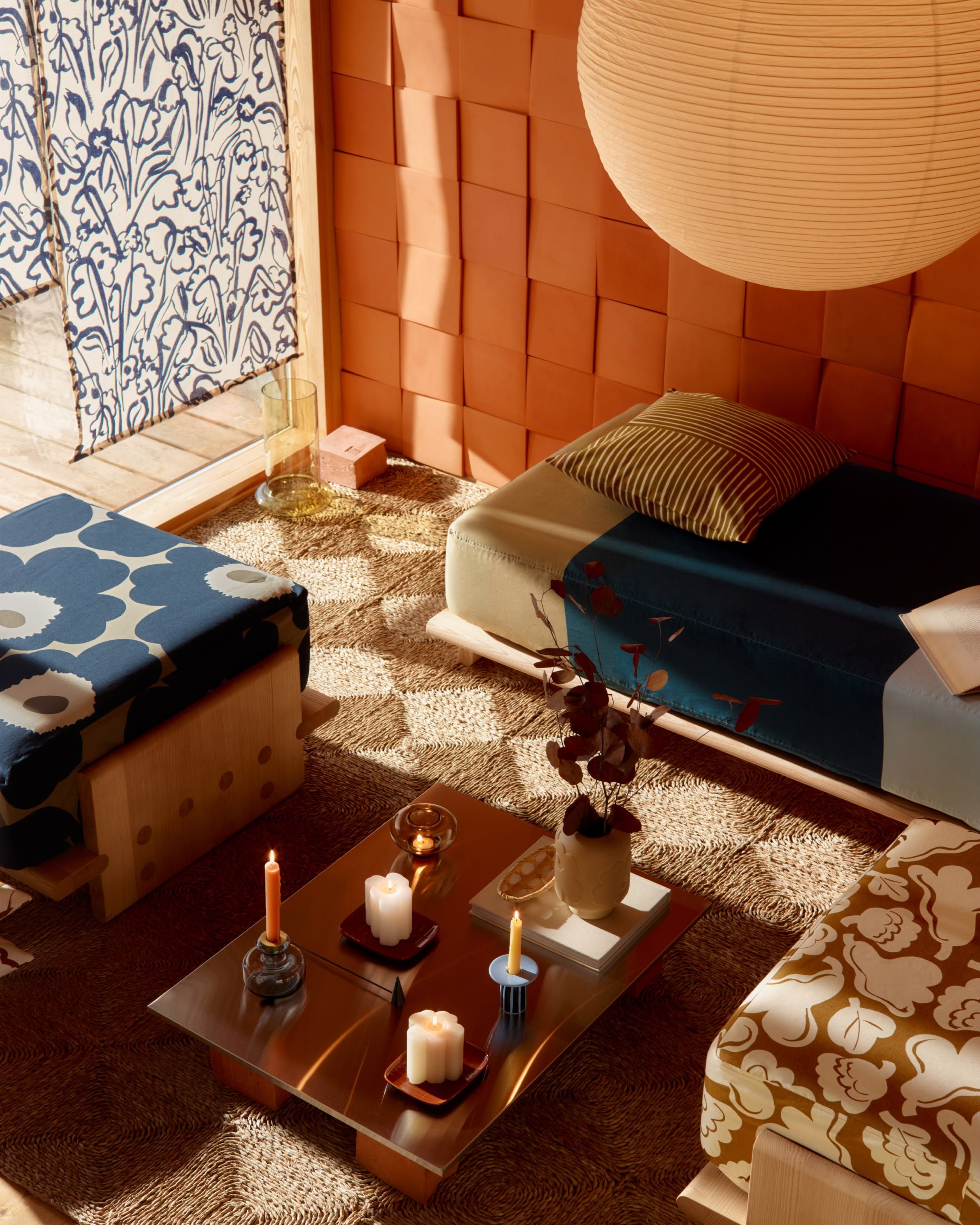 Living room with sofa cushions in Marimekko fabrics featuring Unikko, Hennika, and Kukasta Kukkaan prints, around a table decorated with Marimekko candle holders.