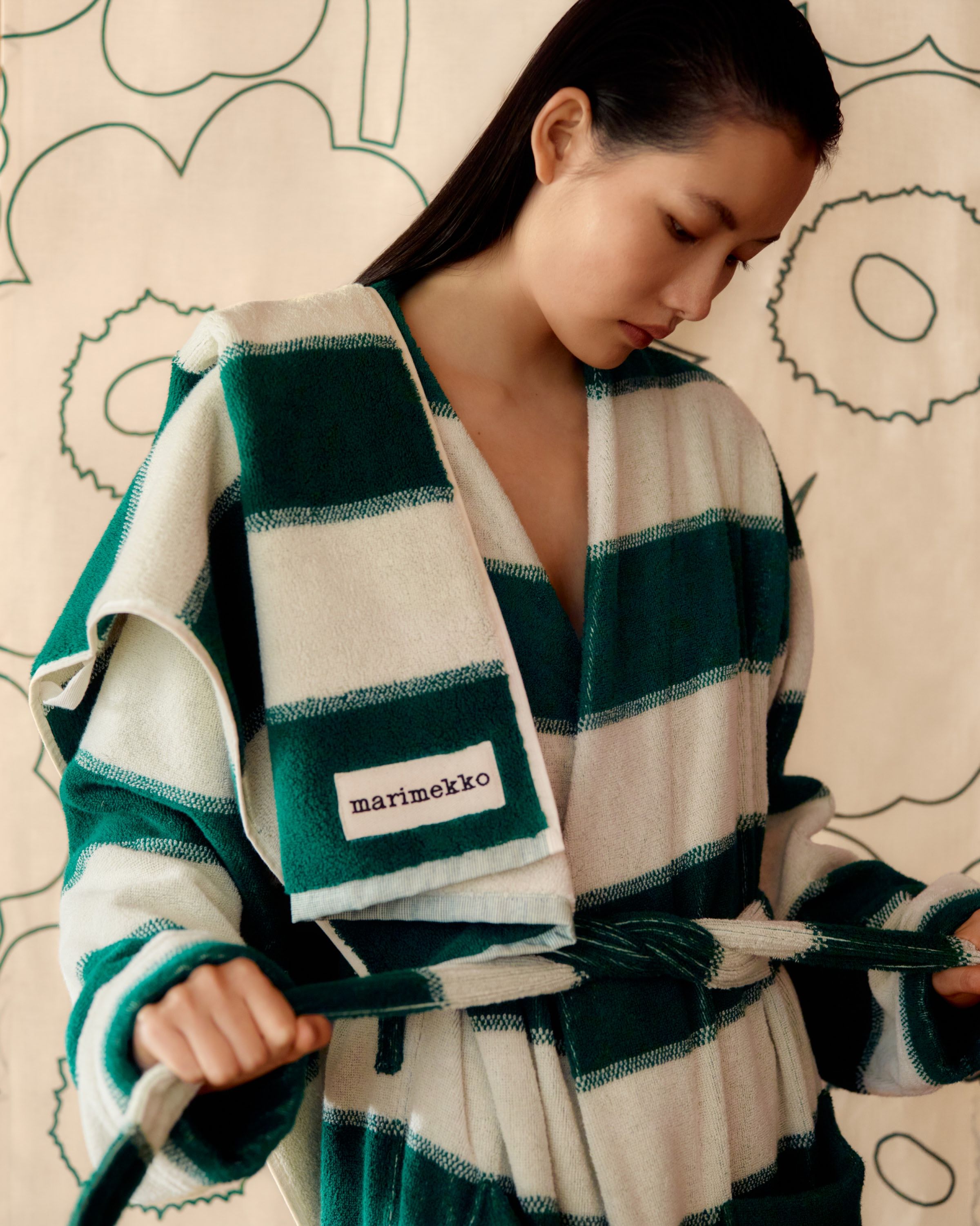 Model wearing a green and white Galleria-print terry bathrobe with a matching towel over her shoulder.