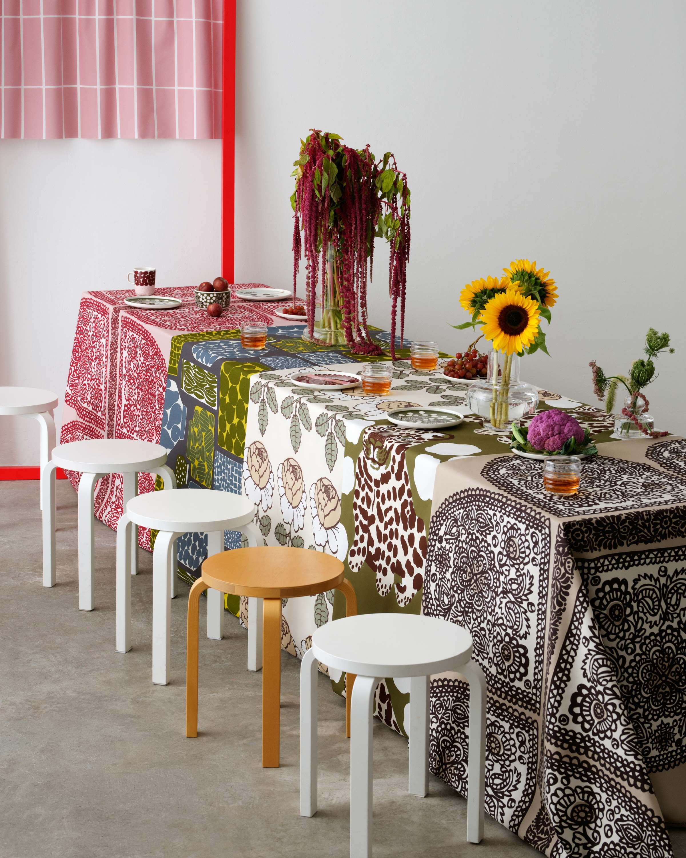 On the long table, tablecloths are displayed in different patterns: Satula, Purnukka, Maalaisruusu and Kaksoset.