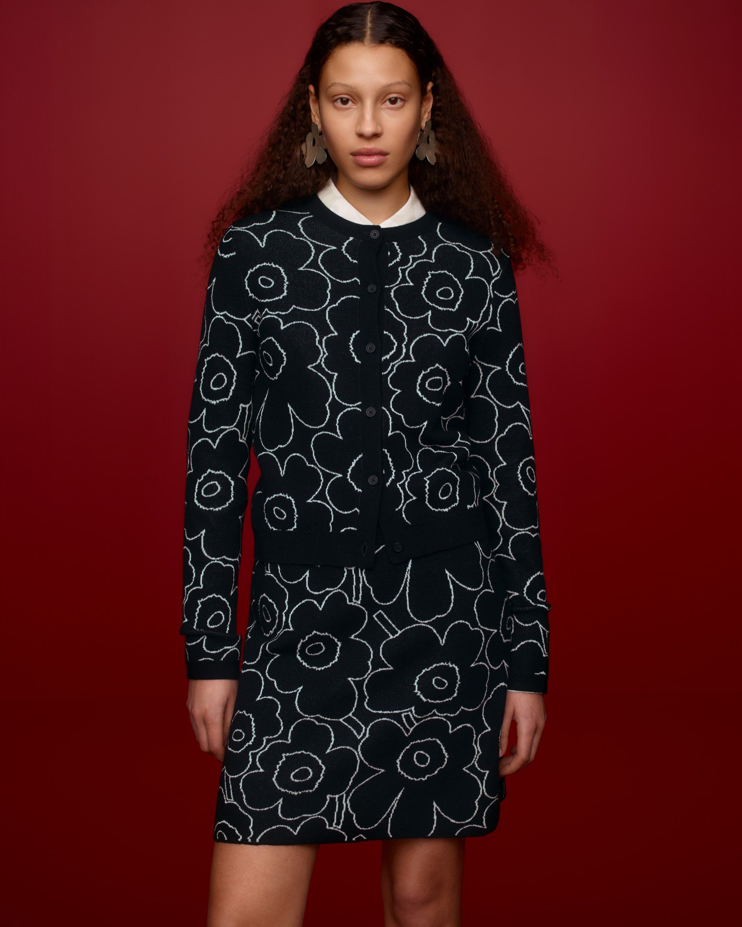 Model wearing a matching set of a cardigan and a knitted skirt in black and white Piirto Unikko print. 