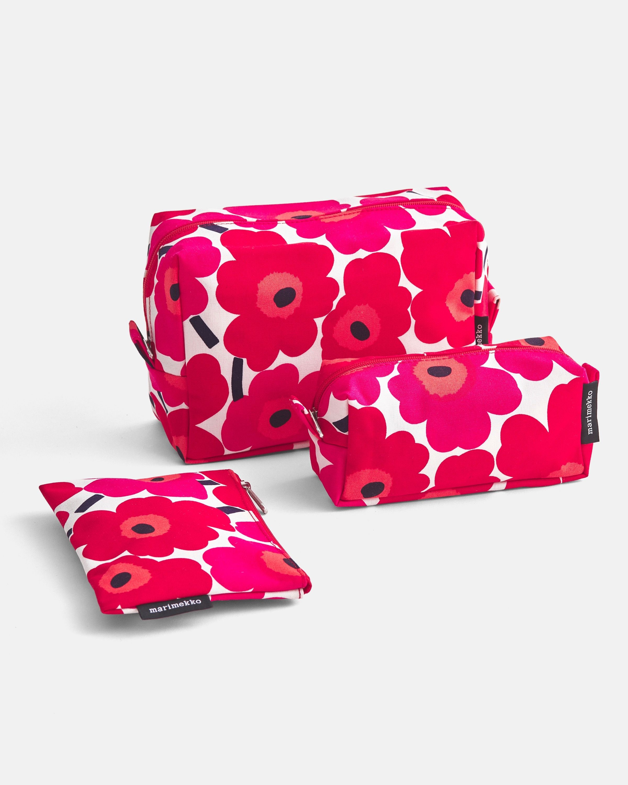 Red and white colored Unikko cosmetic bags in three different sizes.