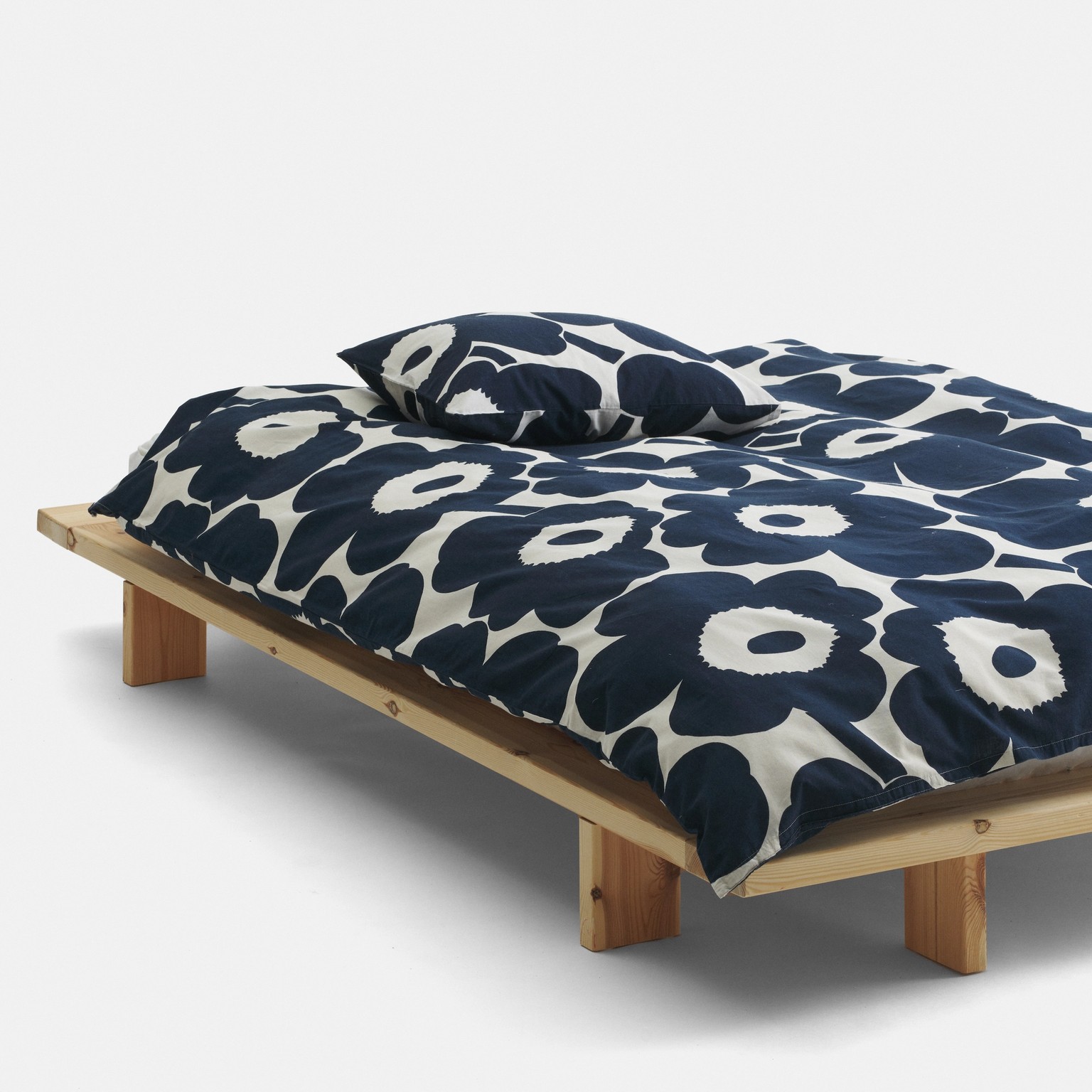 Bed with blue and white bed linen in Unikko pattern.