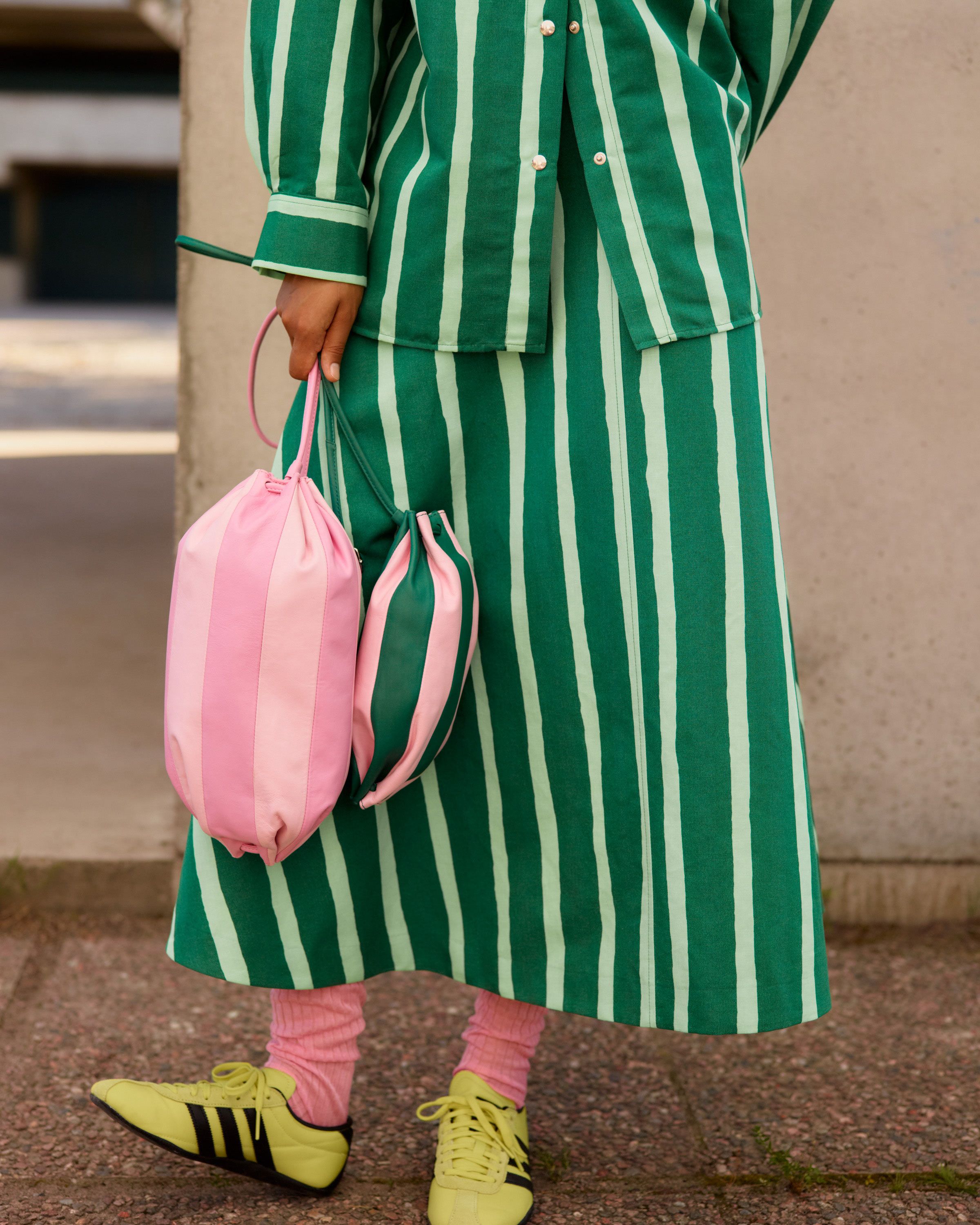 Model holding a pink Karla Multi and a green Pikku Karla Multi leather bag.