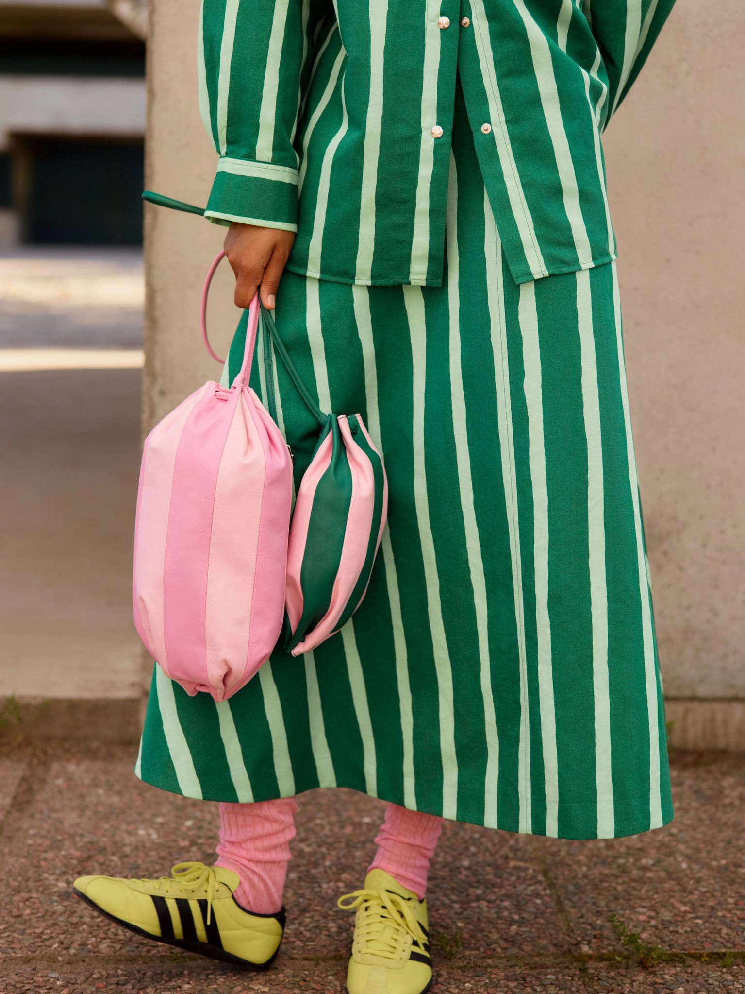 Model holding a pink Karla Multi and a green Pikku Karla Multi leather bag.