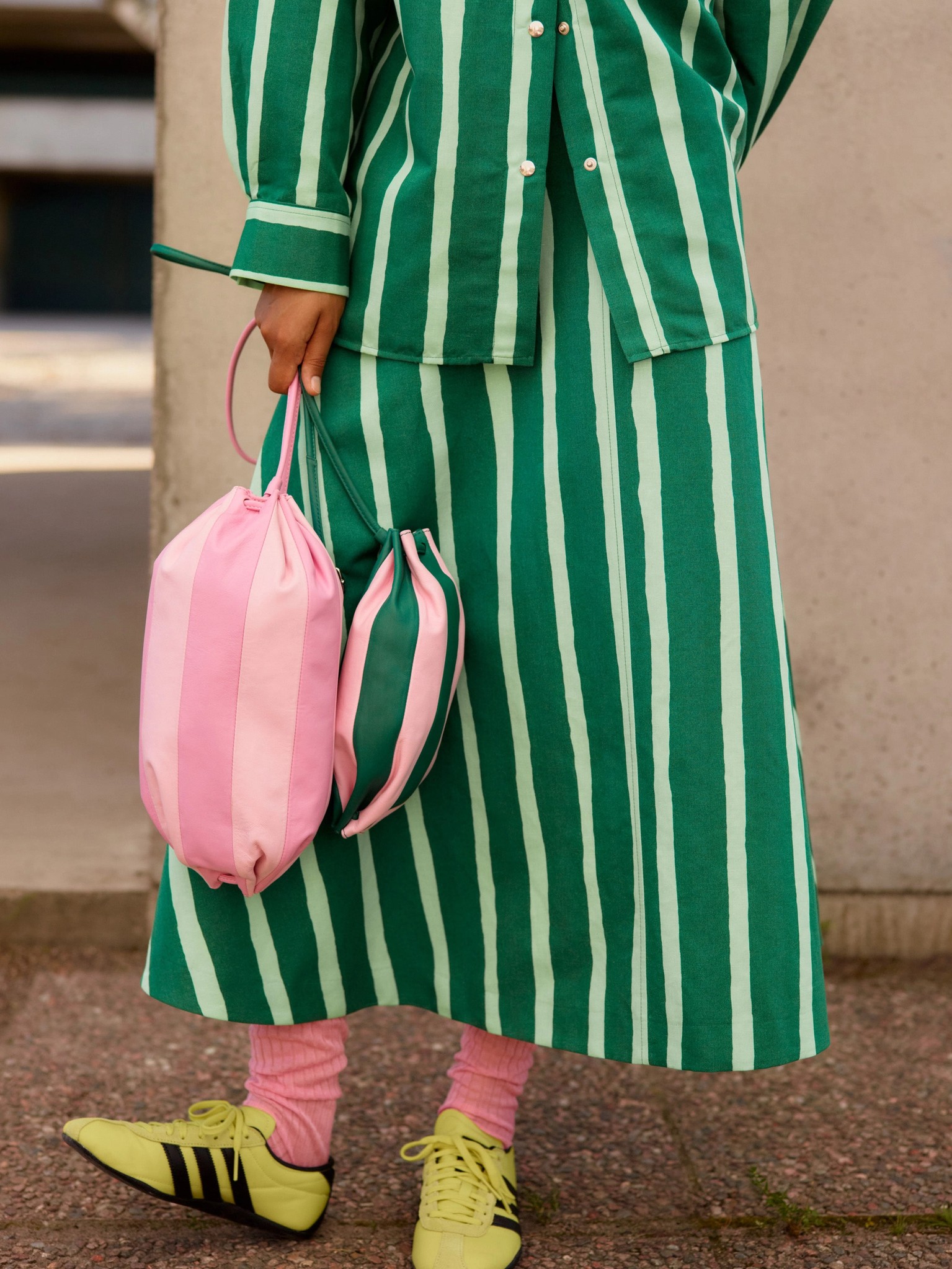 Model holding a pink Karla Multi and a green Pikku Karla Multi leather bag.