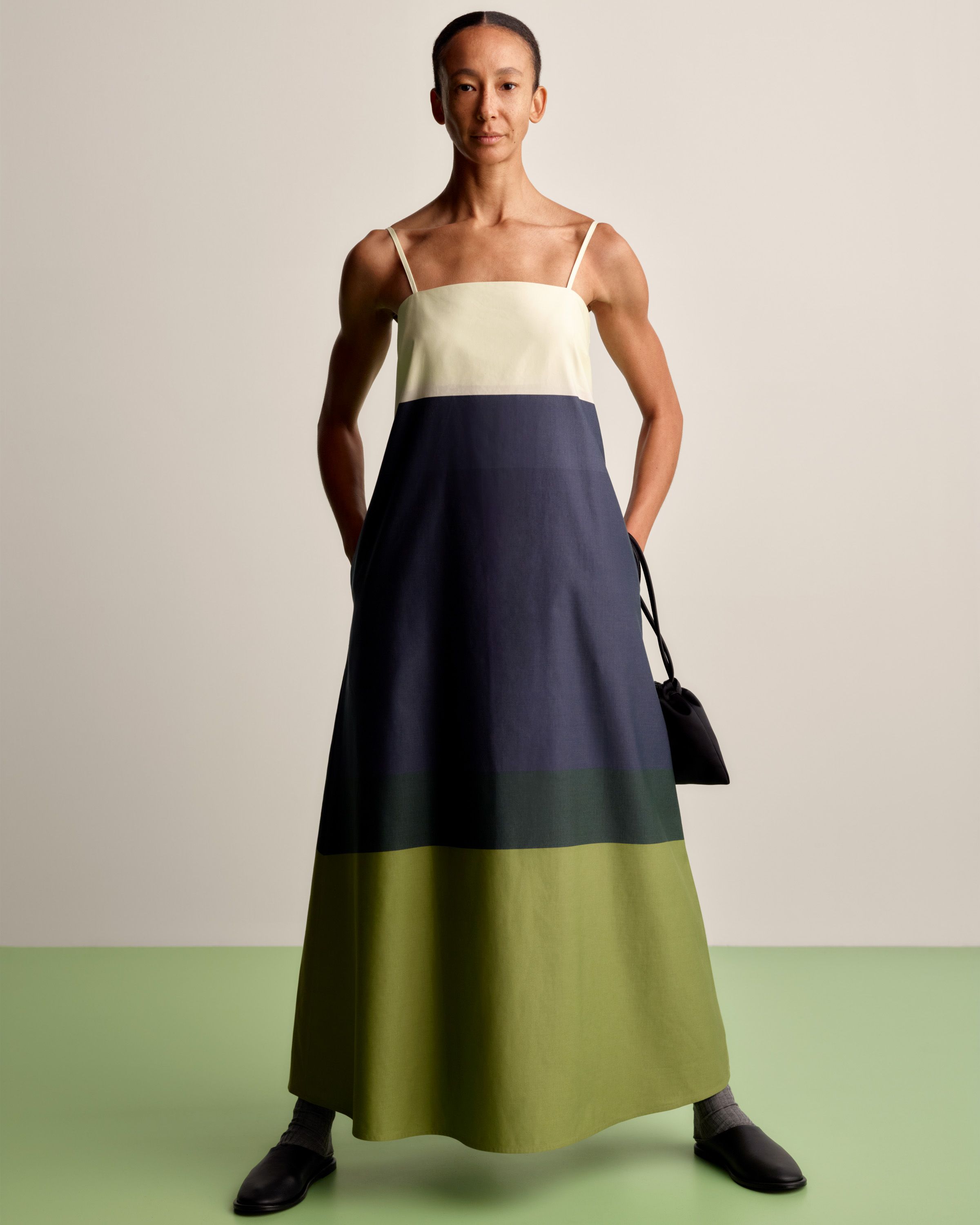 Model wearing a sleeveless long dress in white, dark blue and green Hennika print.