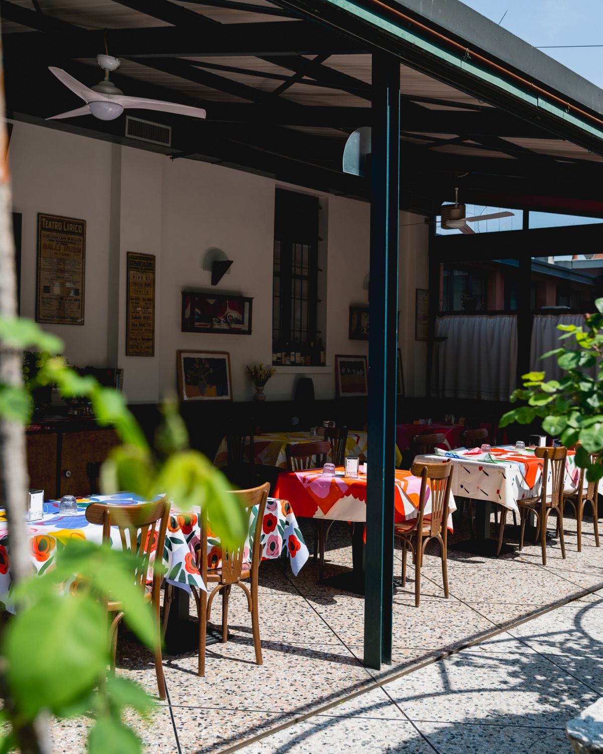A restaurant terrace with tables covered in colorful tablecloths.