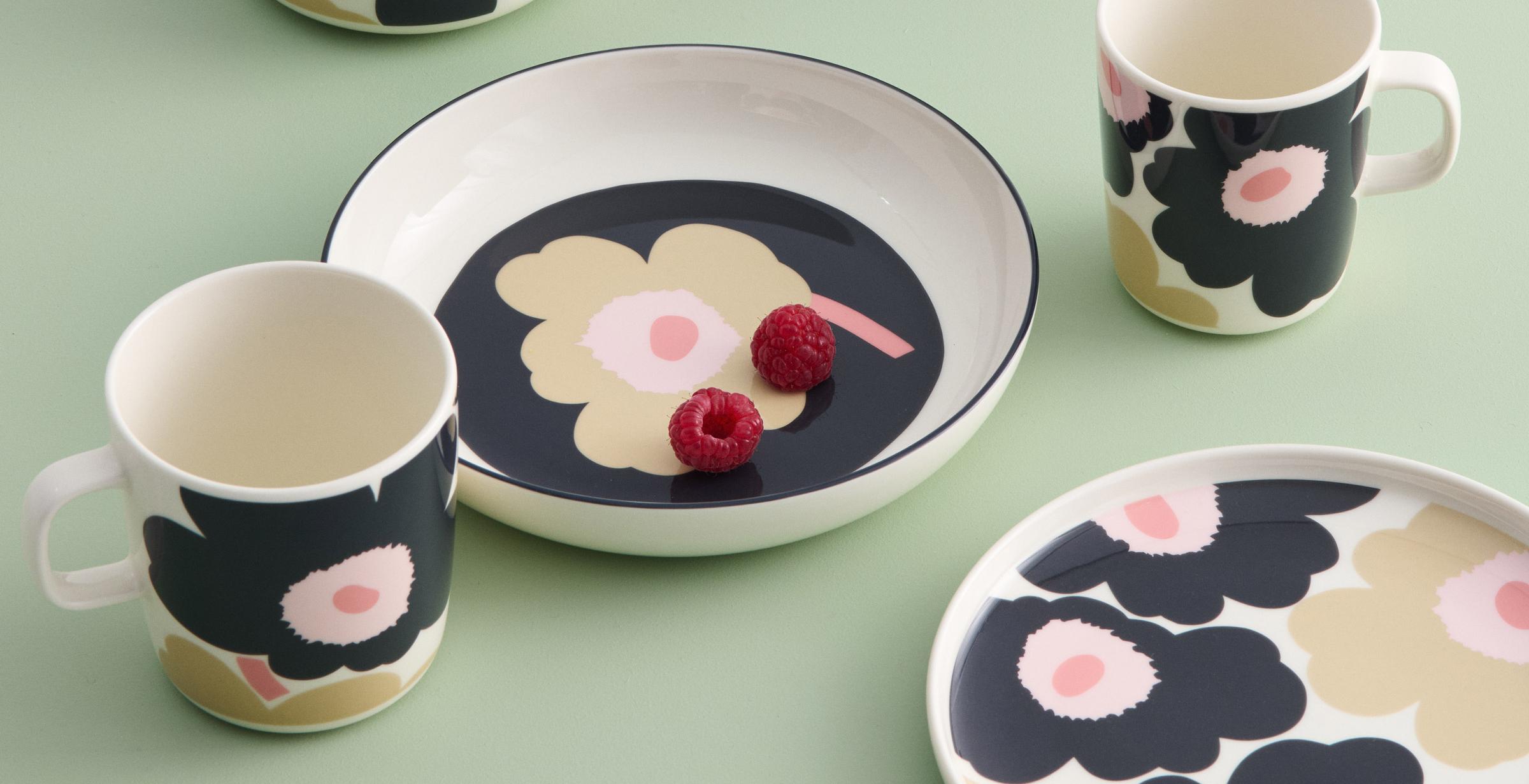 Black and Sand colored tableware with Unikko pattern on a light green table.