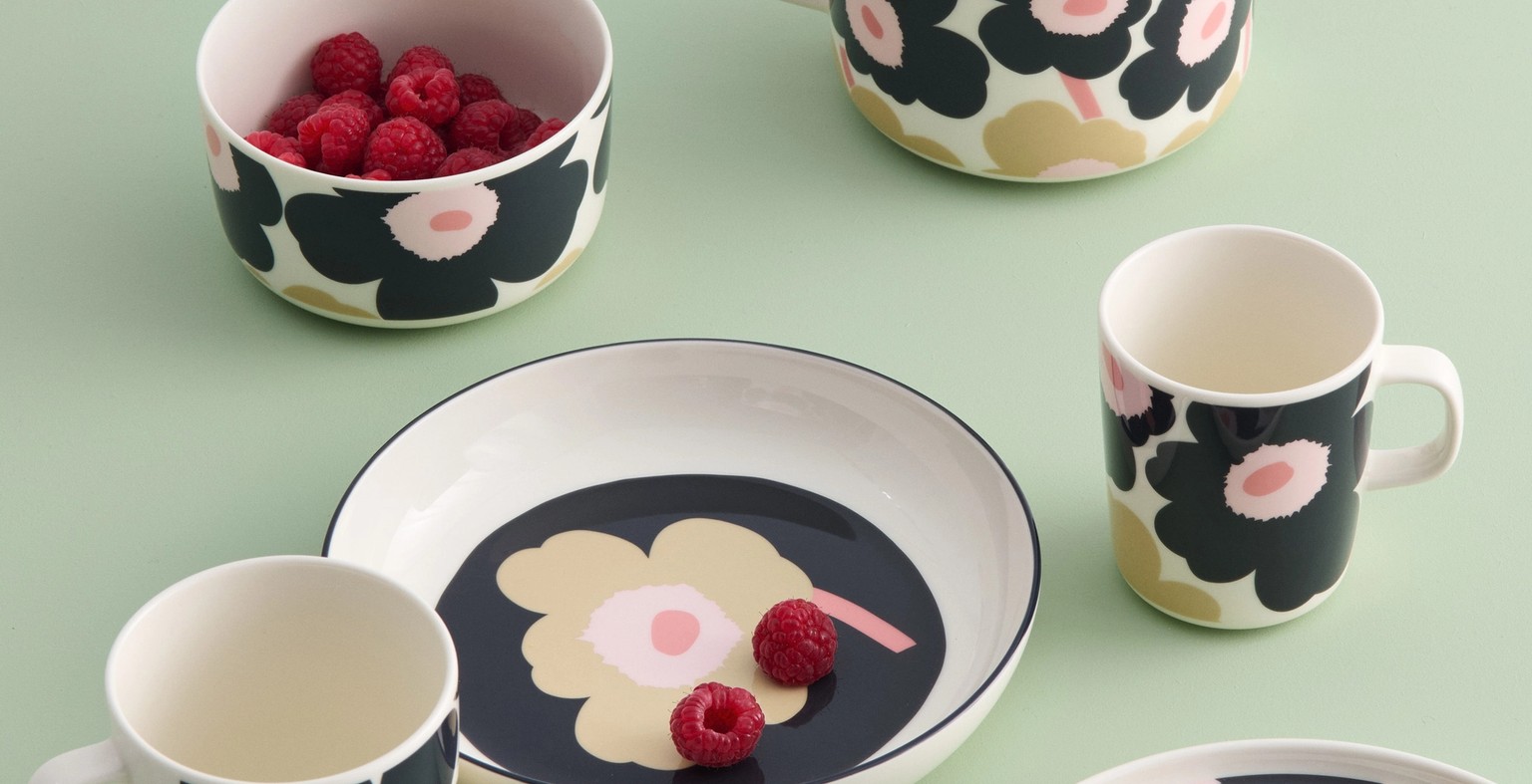 Black and Sand colored tableware with Unikko pattern on a light green table.