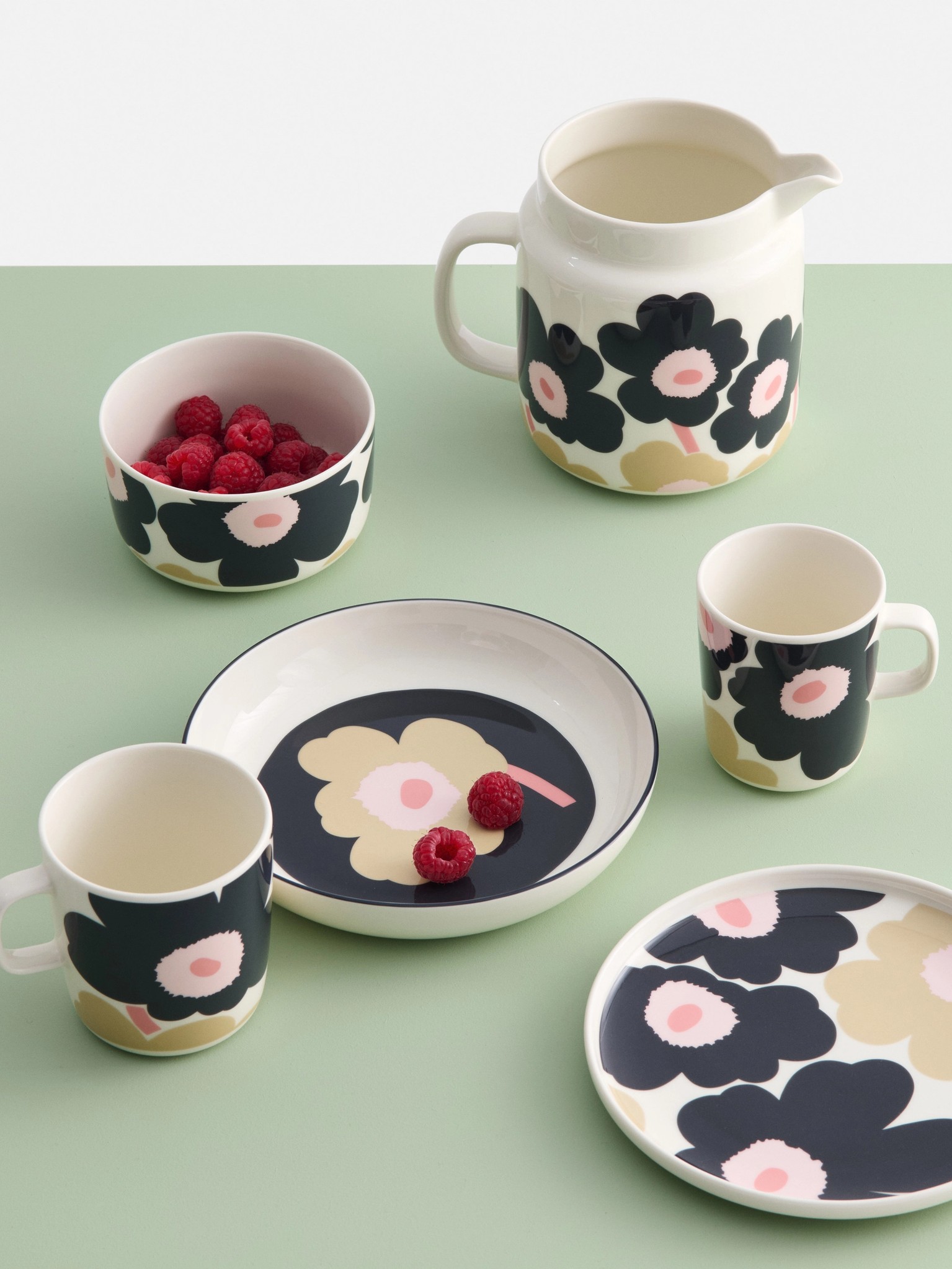 Black and Sand colored tableware with Unikko pattern on a light green table.