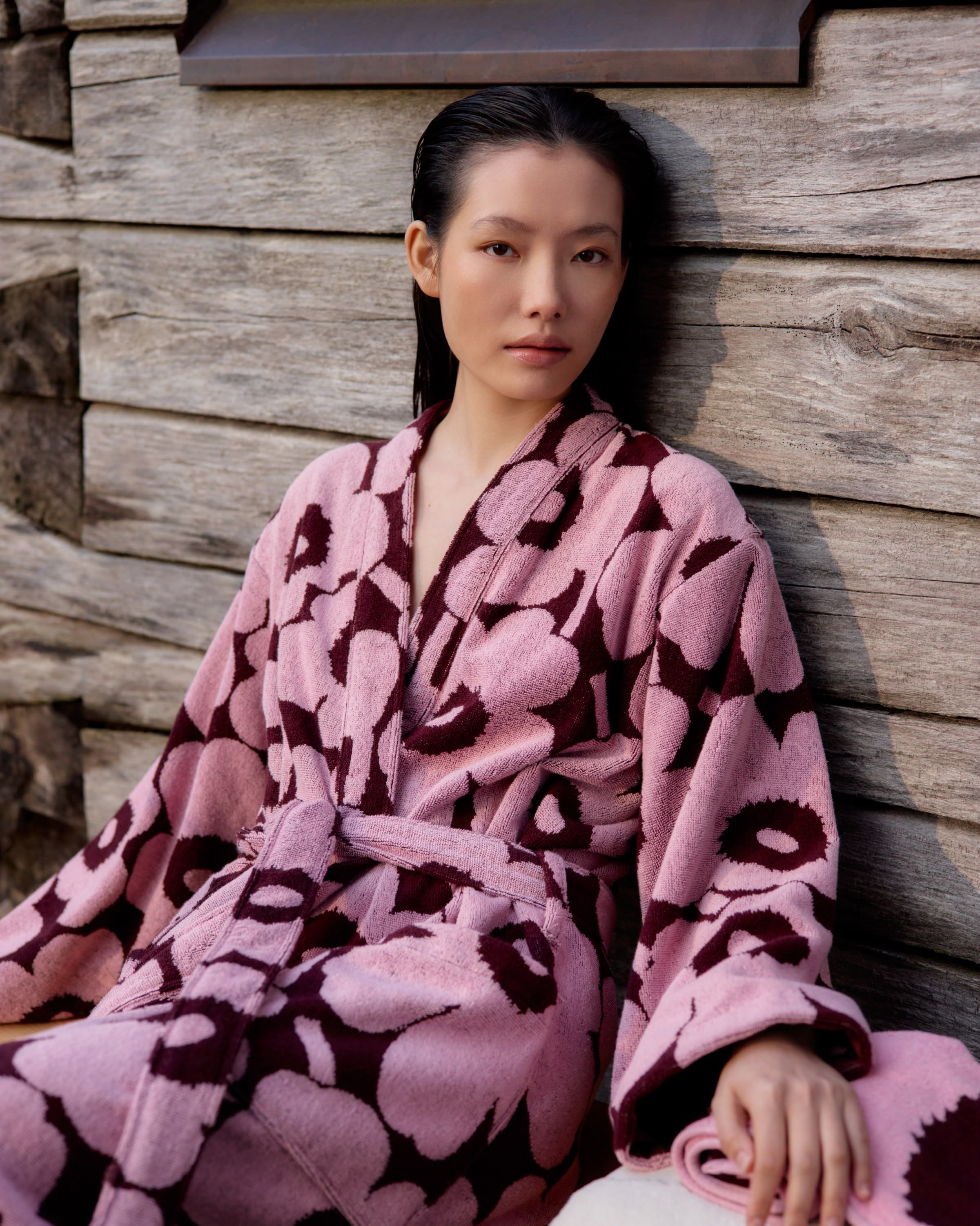 Model wearing a red and pink Unikko-print bathrobe outside.