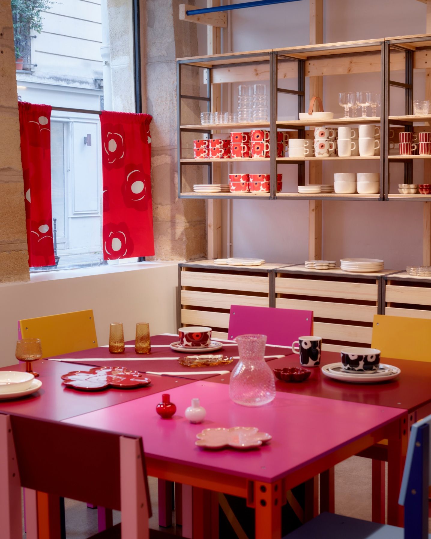 Display of Marimekko home items such as mugs, plates, tumblers.